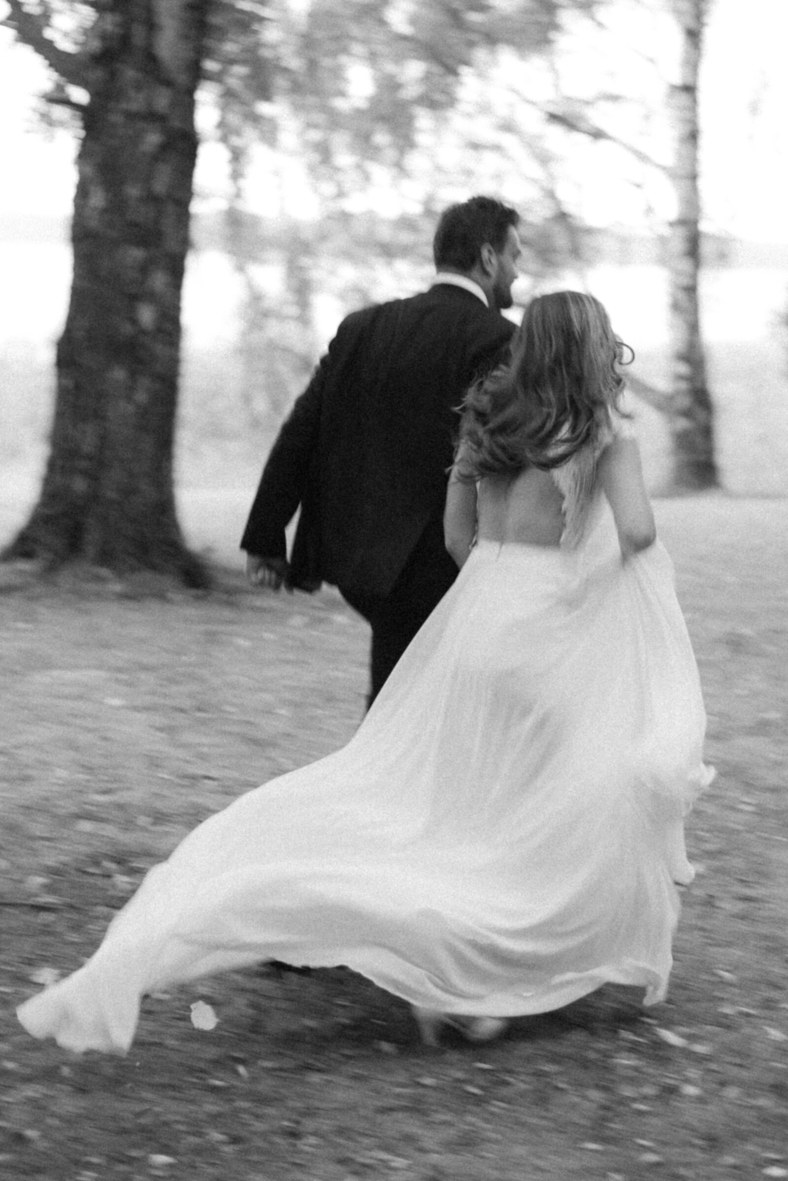 A wedding photograph of bride and groom running during their photo shoot. The tail of the wedding dress flutters in the wind. An image photographed by wedding photographer Hannika Gabrielsson.