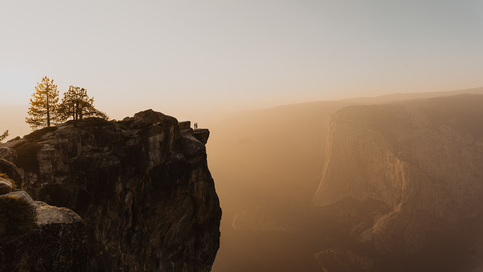 A couple eloping in yosemite stands at taft point during sunset