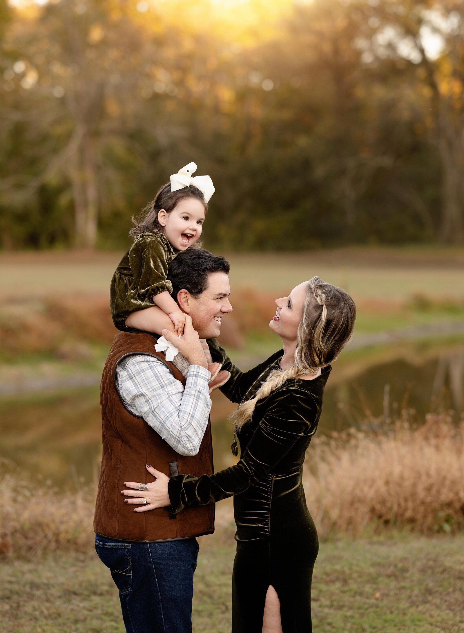 Baby on Dad's shoulders and smiling at Mom.