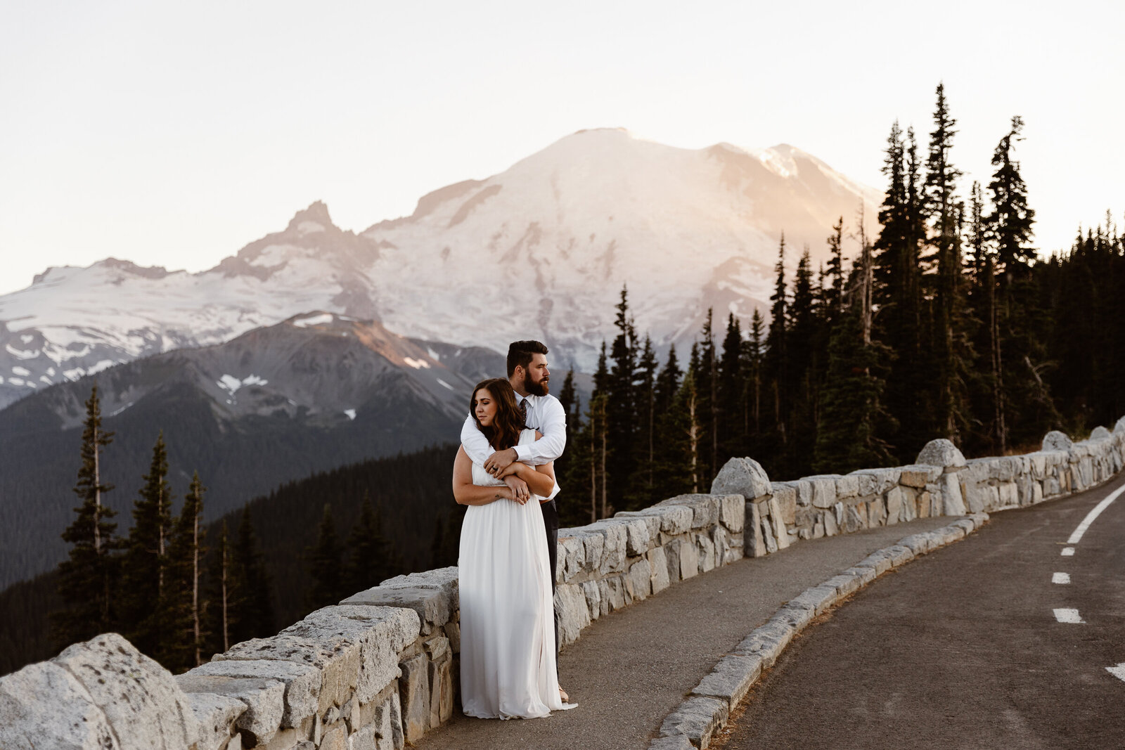 a couple stands on a road in front of Mount Rainier at sunset during their Washington elopement