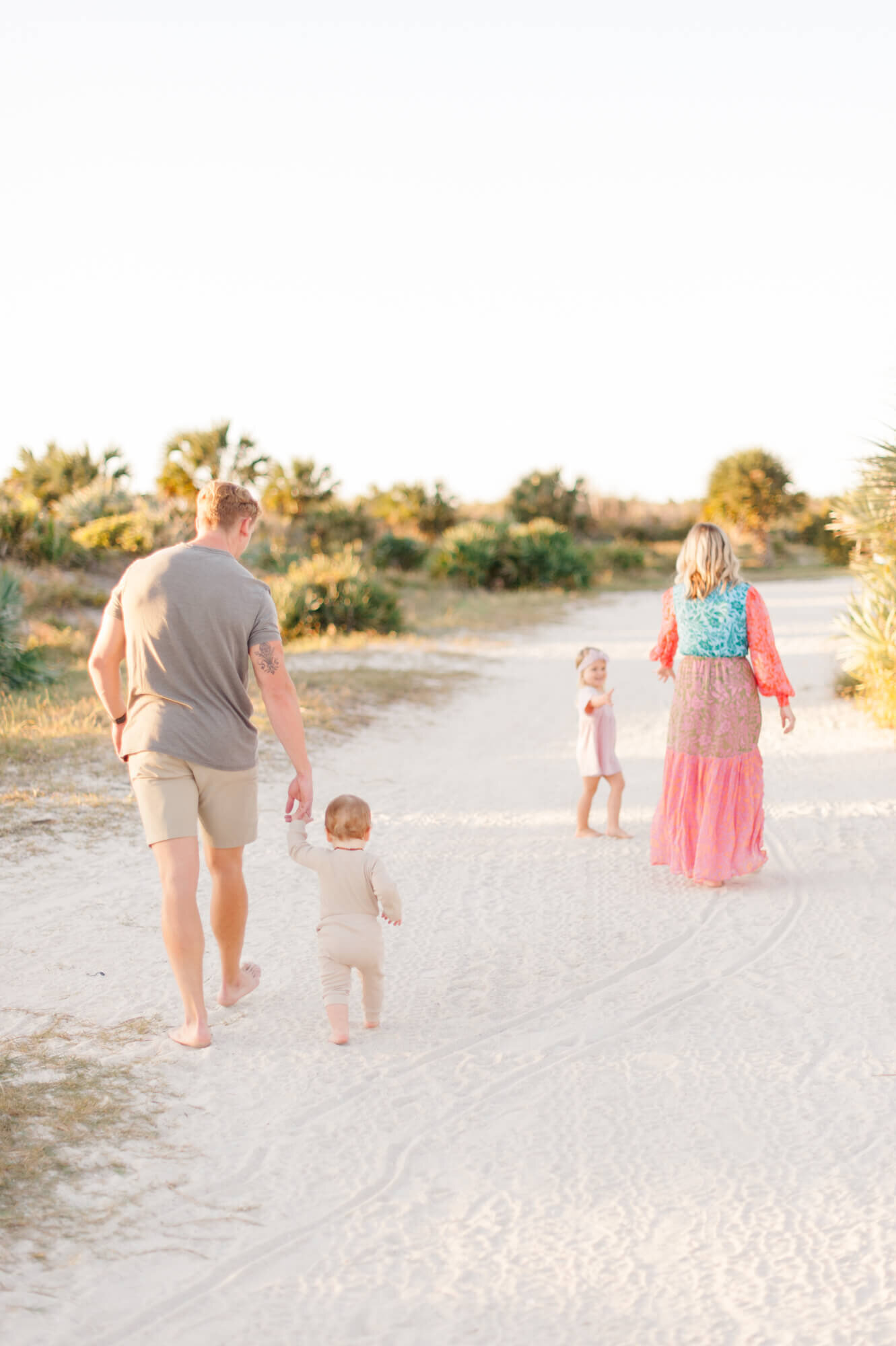 Family of four walking toward the beach holding hands