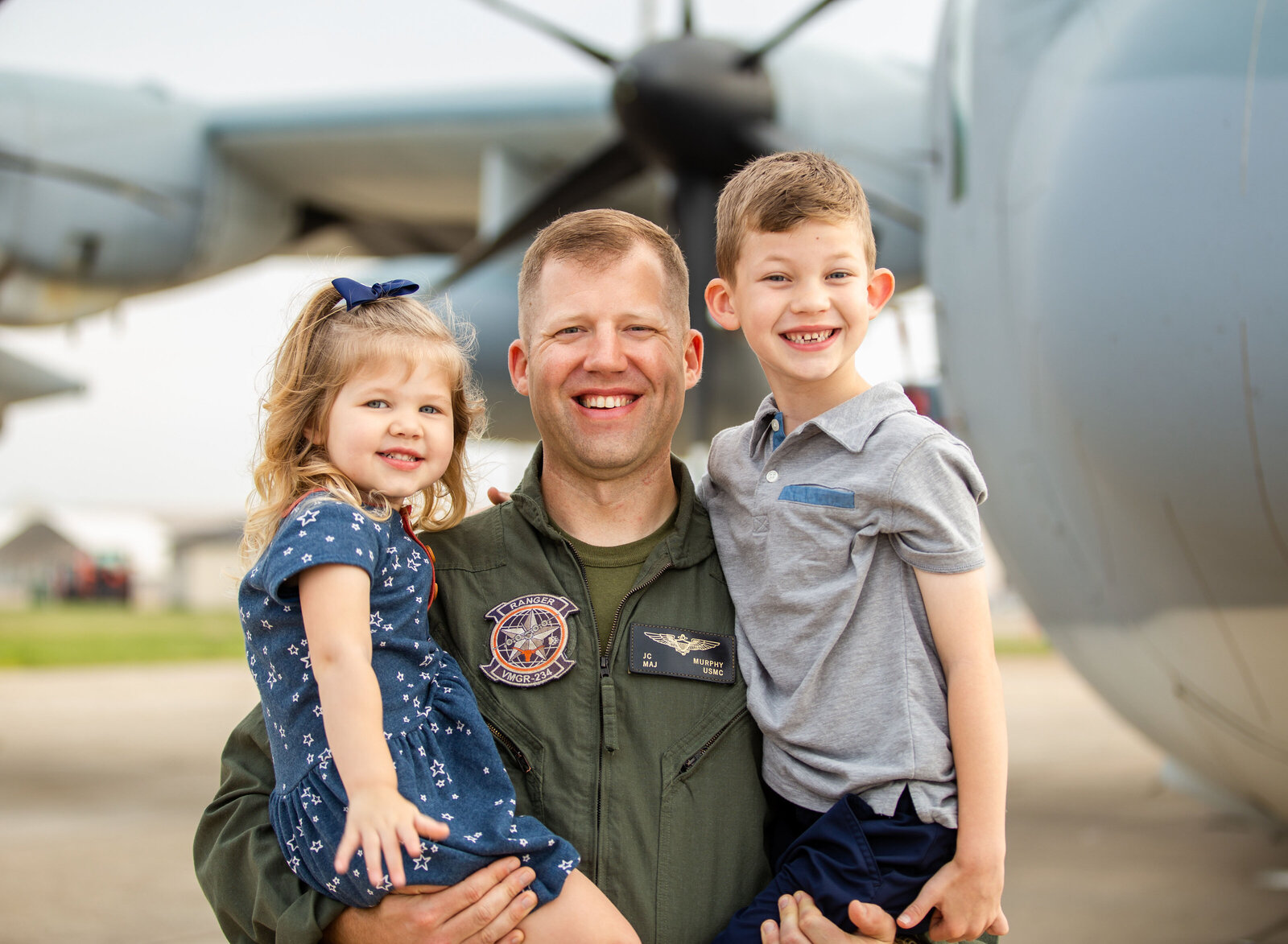 air force dad holding kids by plane