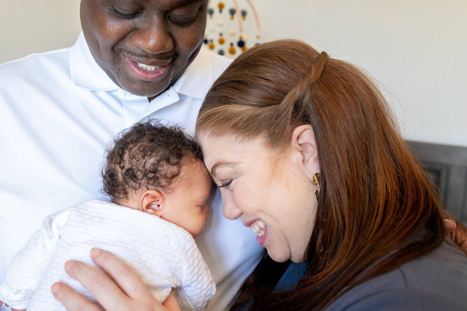 A close-up of mom and dad snuggling with their newborn baby boy in their Woodbridge home.
