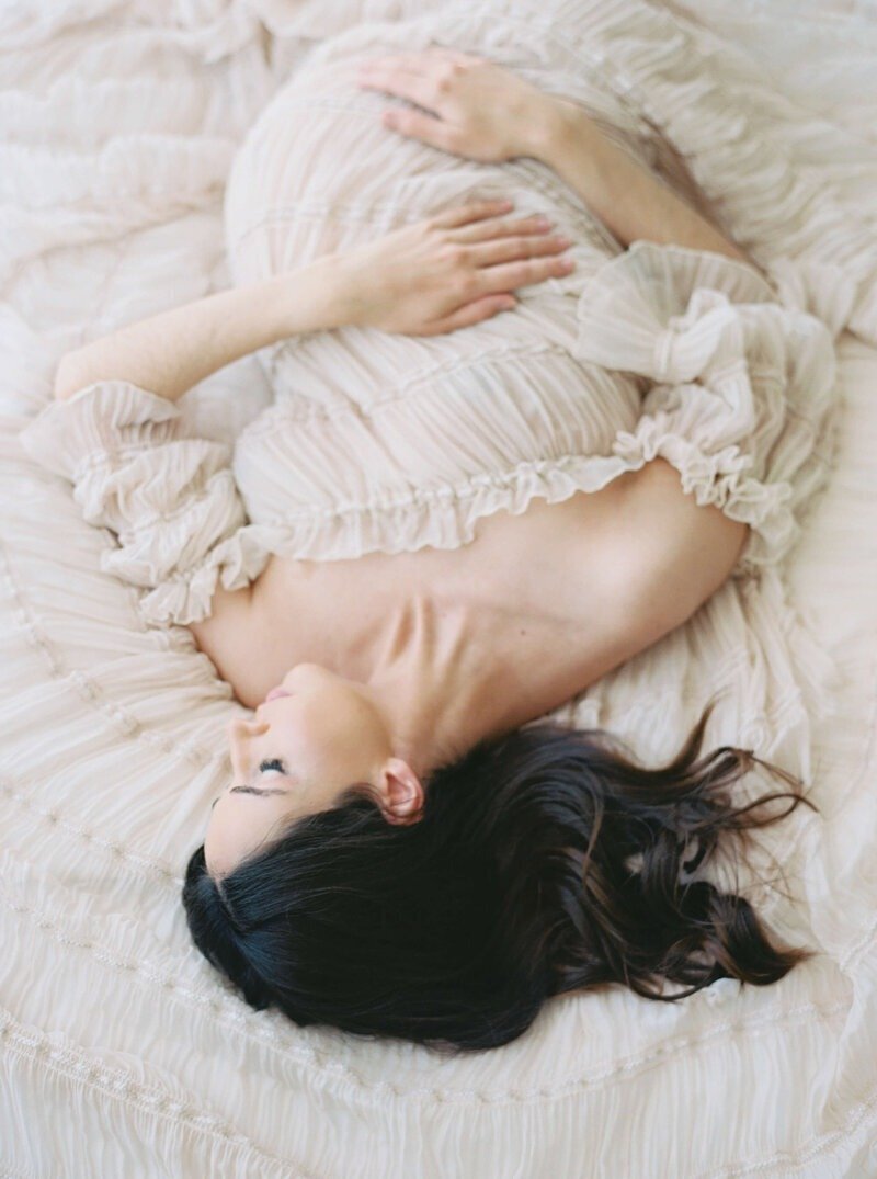A serene studio maternity portrait with the expectant mother in a simple, elegant gown, captured by San Francisco Maternity Photographer, Laurel Smith.