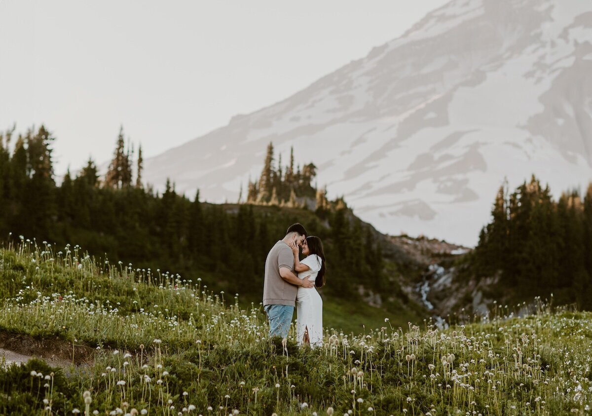 A moment captured by a Cannon Beach Wedding Photographer of an engaged couple kissing on a cliffside with a stunning view