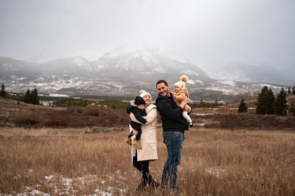 a family dressed in winter coats walks in a mountain field