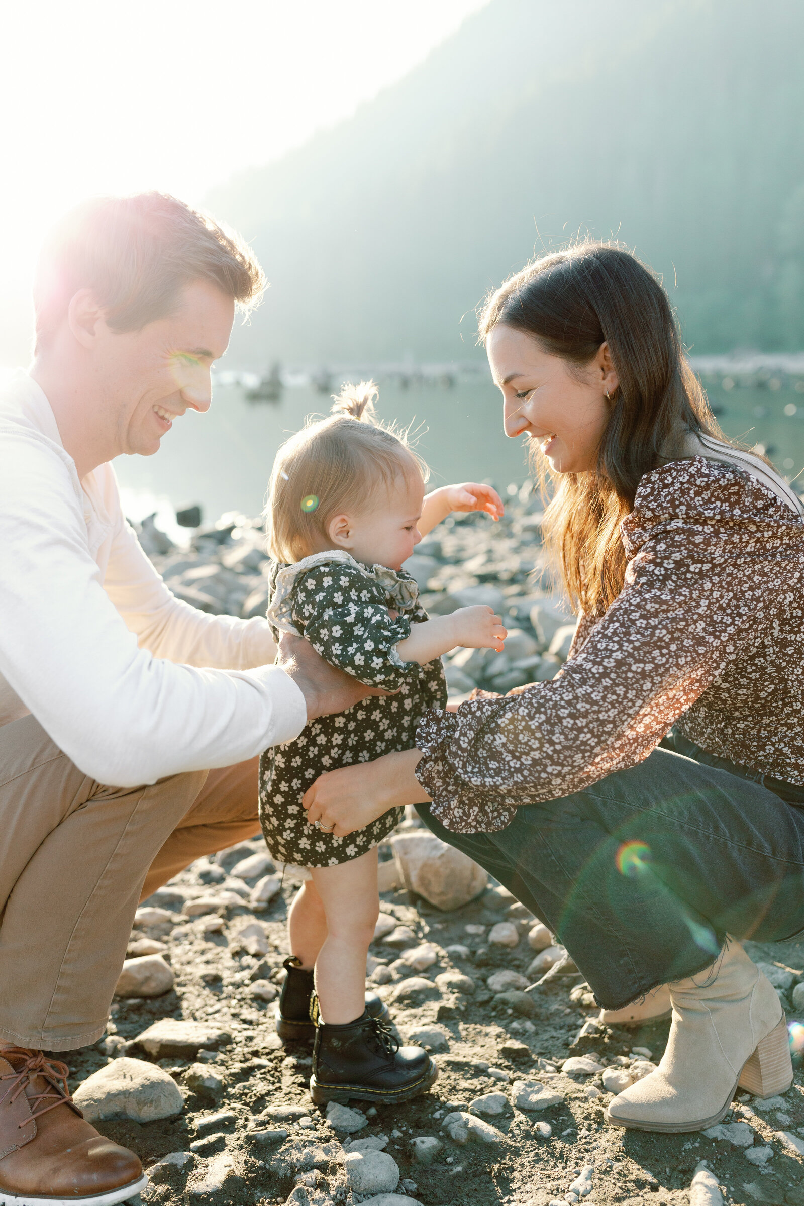 Parents kneeling down with child at golden hour at Rattlesnake River in North Bend.