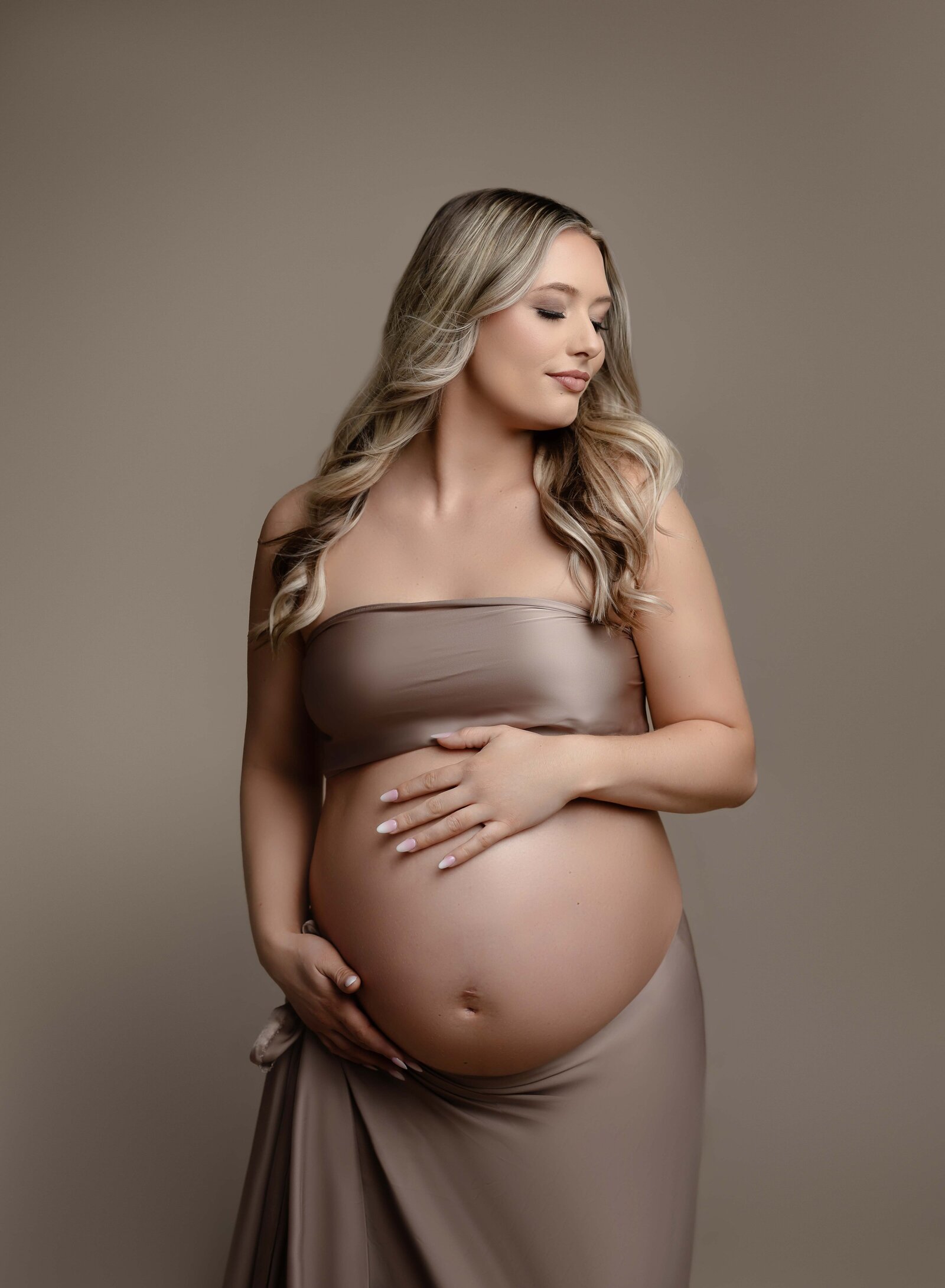 Mom holding baby bump and looking off to the side dreaming of baby. Maternity portrait taken by Jenni. Nikki Photography at Atlanta Photo Studio. 