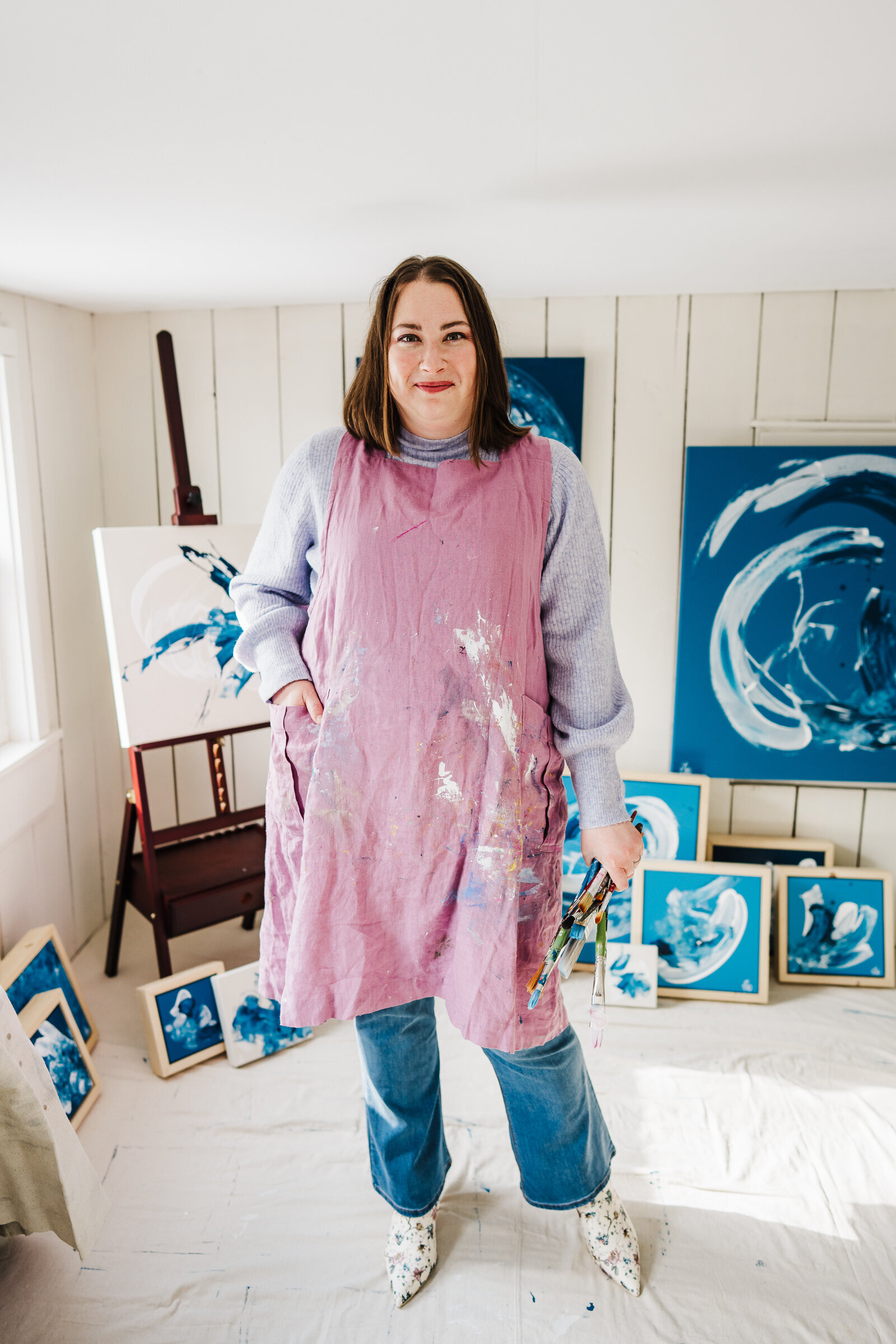 artist in pink smock paints in studio