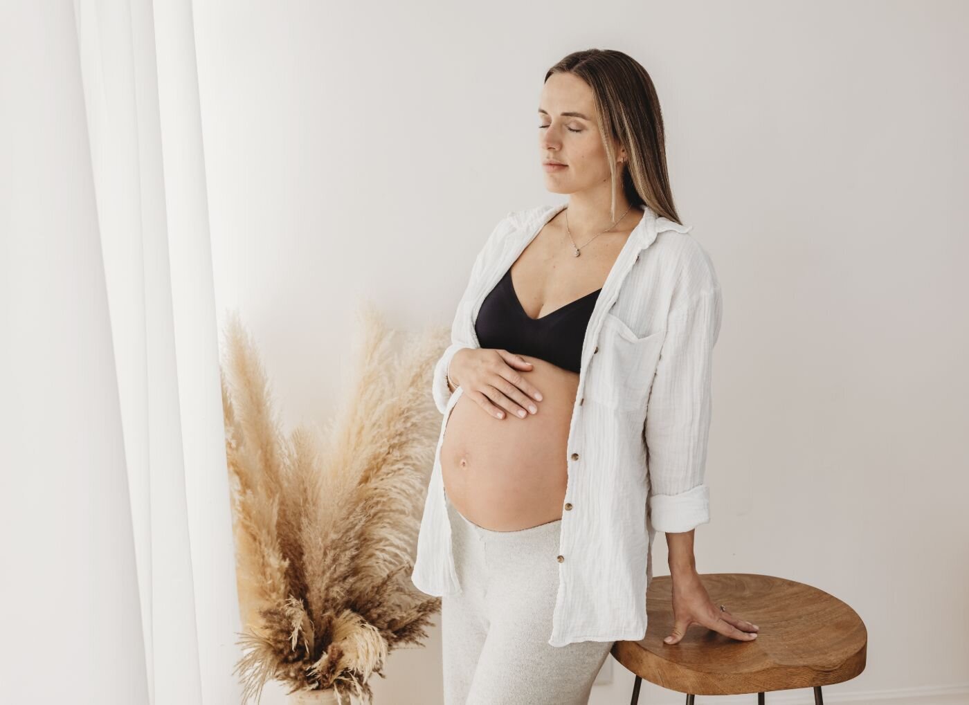 Pregnant woman by window with pampas grass. Altrincham maternity.