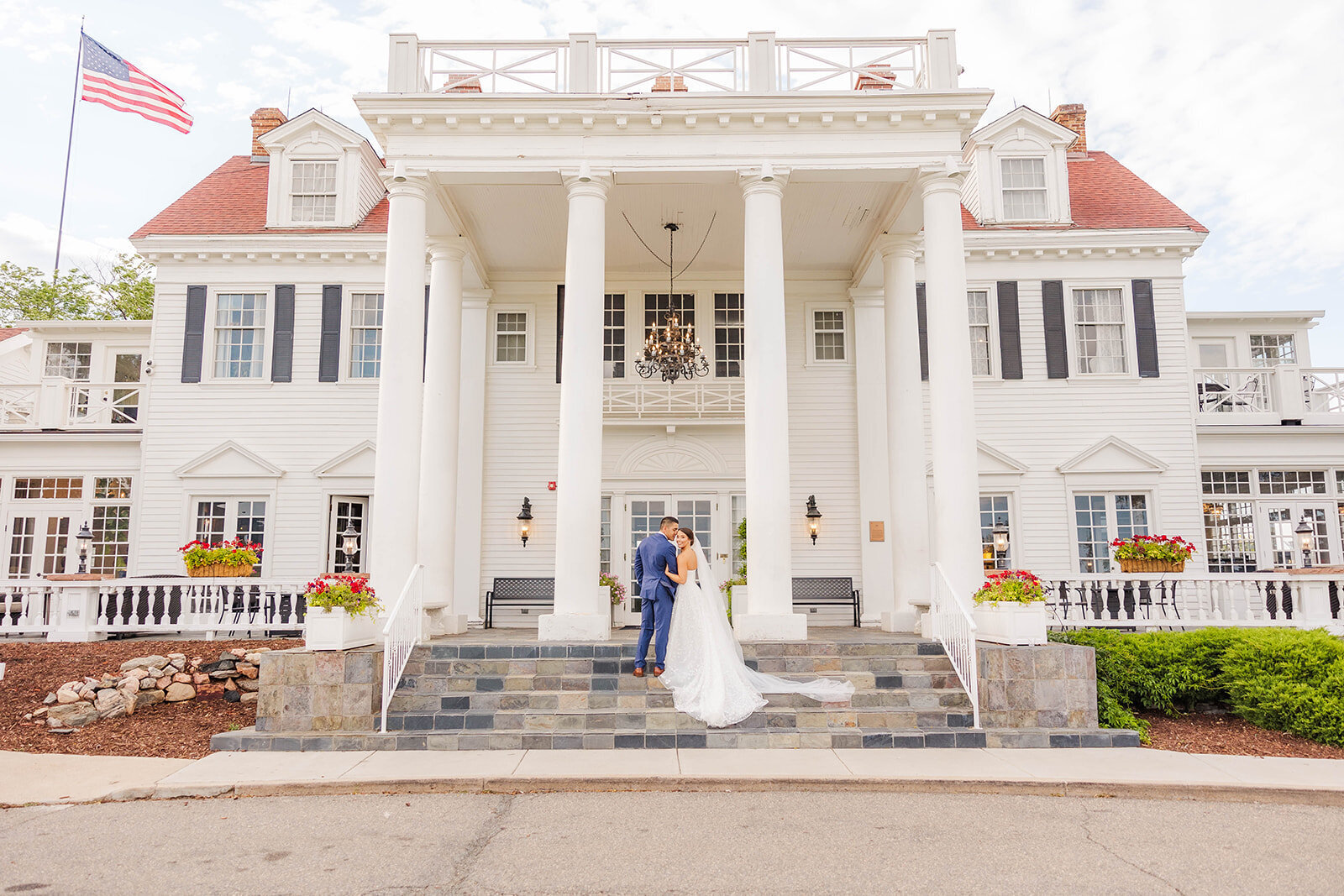 Bride and groom posing together on the steps of the beautiful Manor House on their wedding day in Littleton, Colorado.