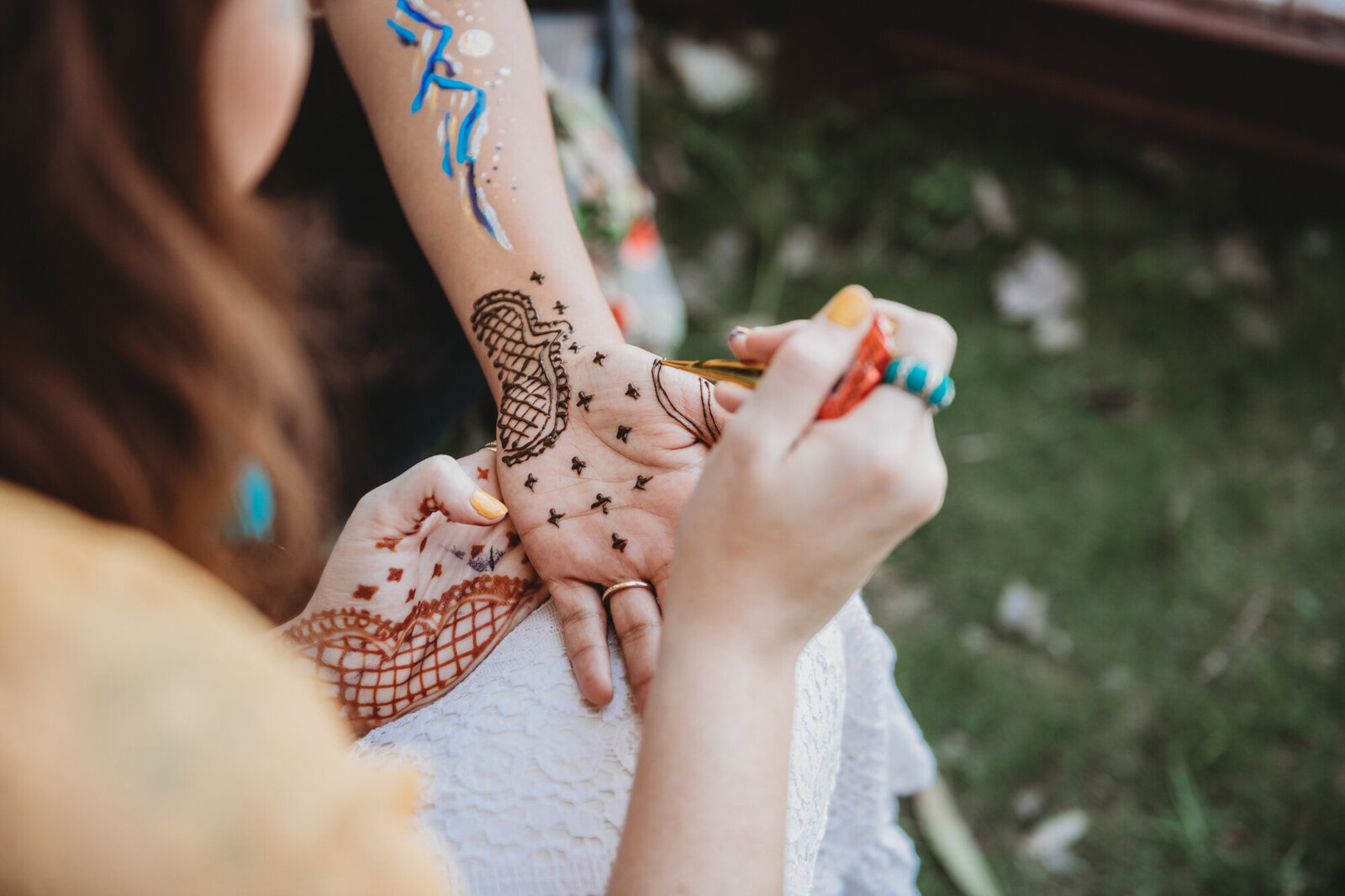 Branding Photographer,  a woman applies henna art to her child's hand