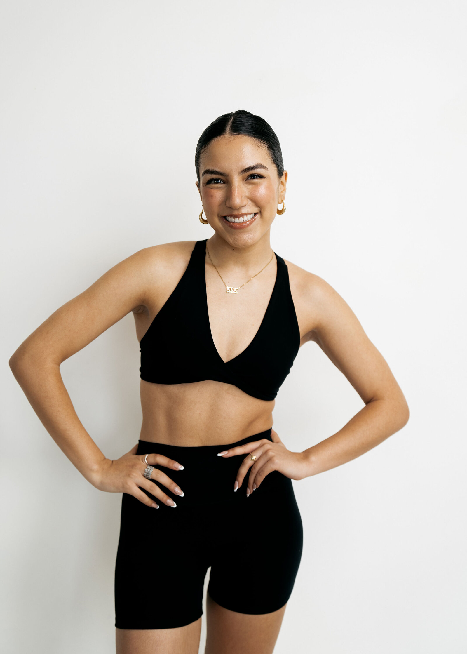 A member standing confidently in black activewear against a pale wall