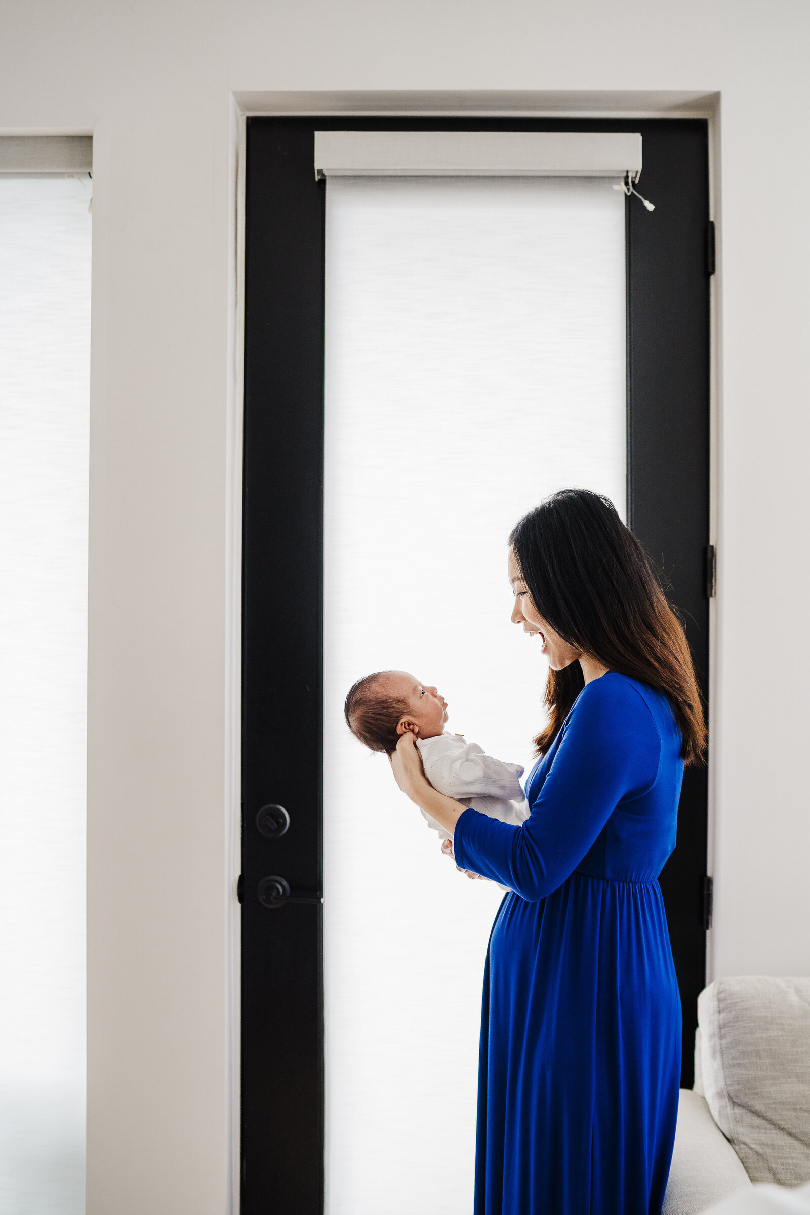 mother stands with new baby in door frame in boston apartment