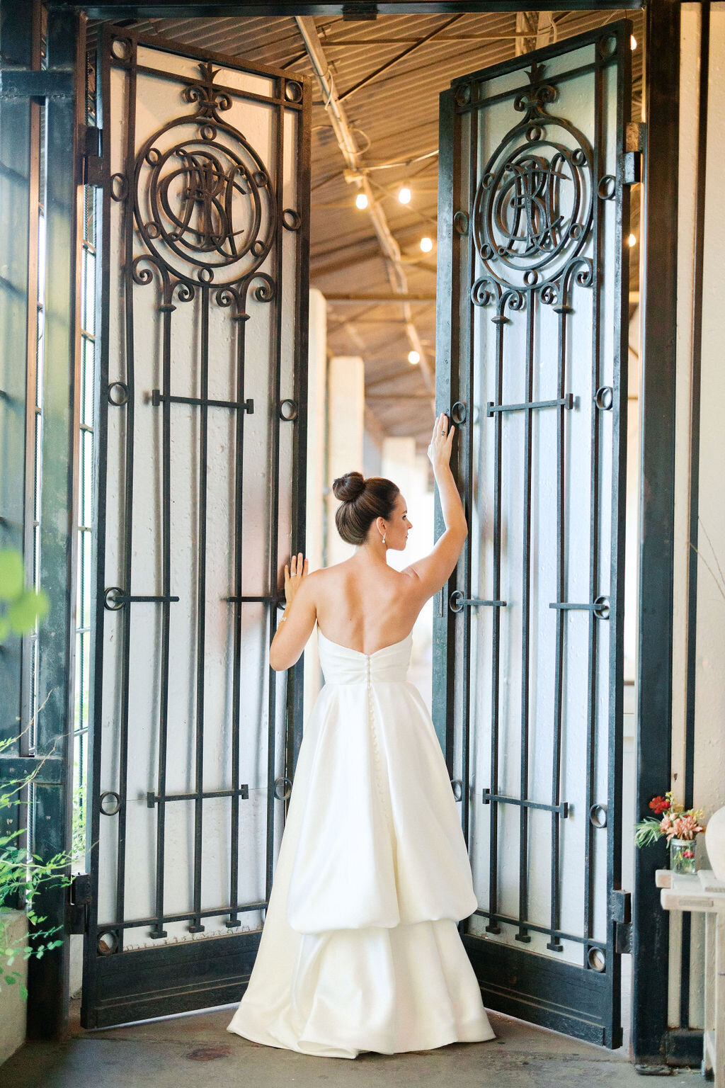 Bride in long white dress opens gates at Westside Warehouse