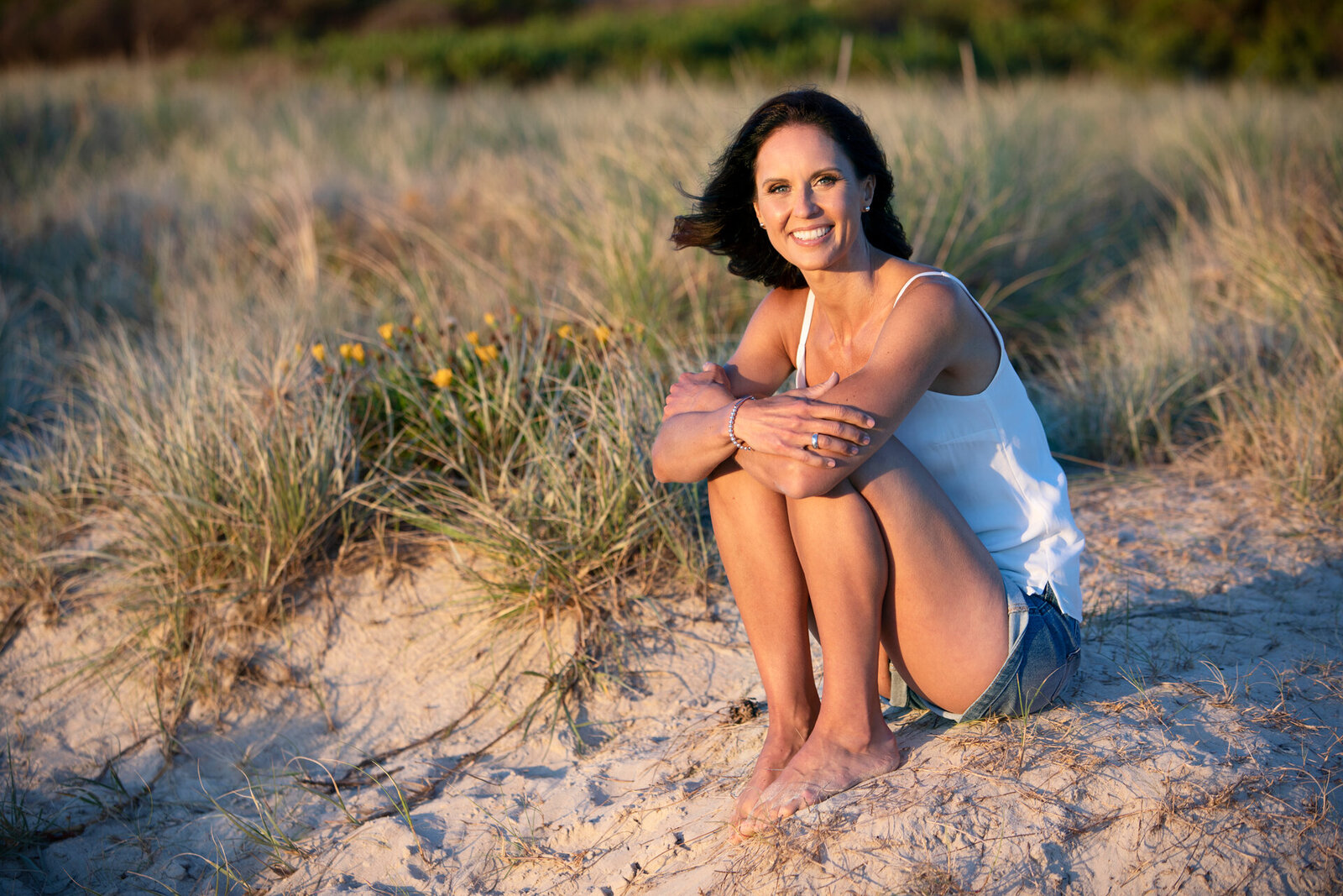 lady sitting in long grass at a beach