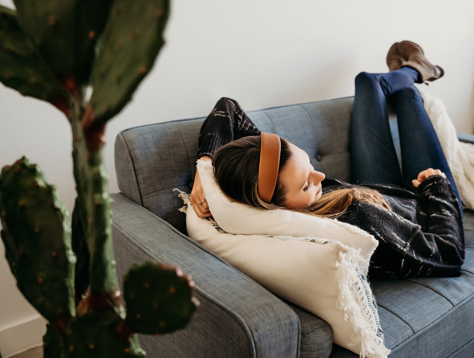 Branding Photographer, a woman lays on a couch in the living room, a cactus plant behind her