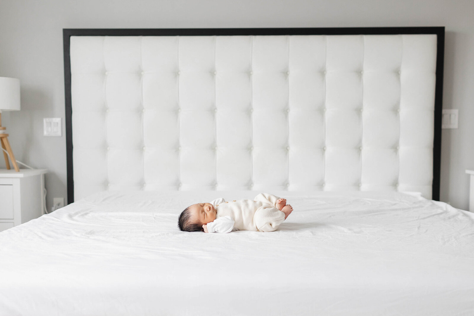 Newborn baby boy stretching  on big bed