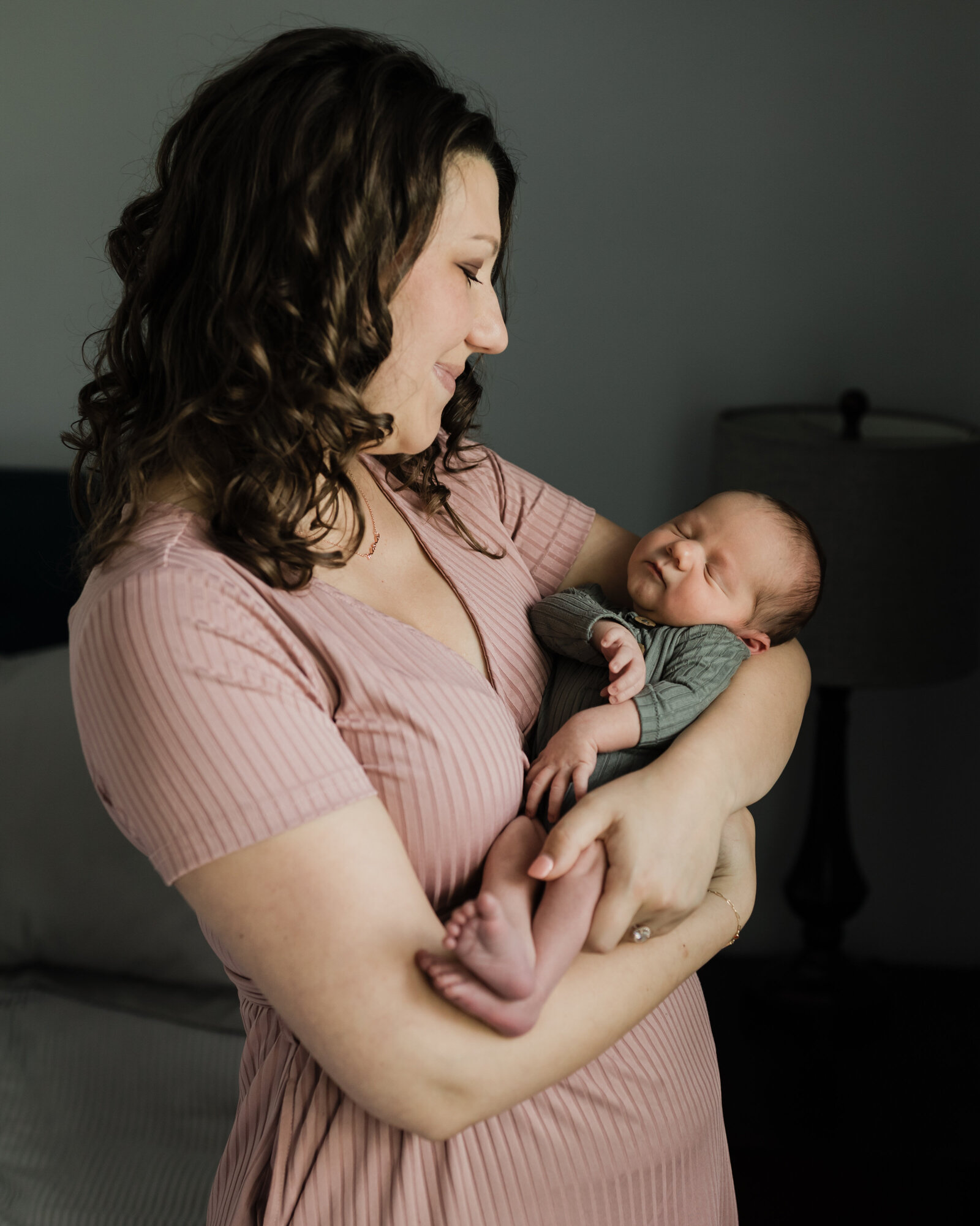 mom cradling newborn baby boy in bedroom for in home lifestyle session 