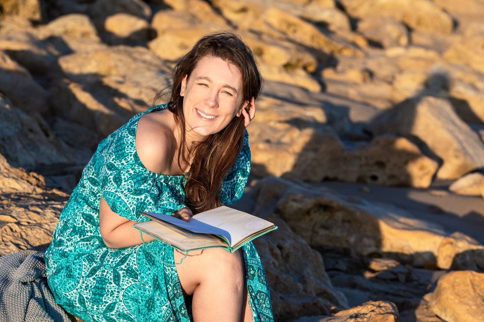 Lady sitting on rocks holding a notebook