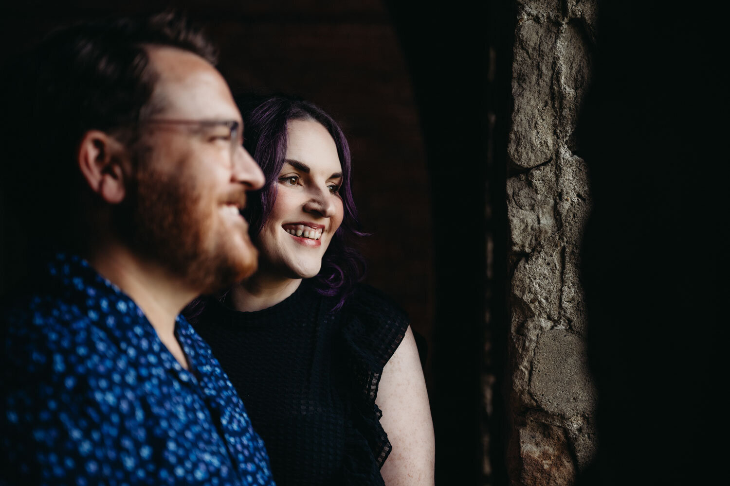 Couple smiles in low key setting by Paige Mireles Photography