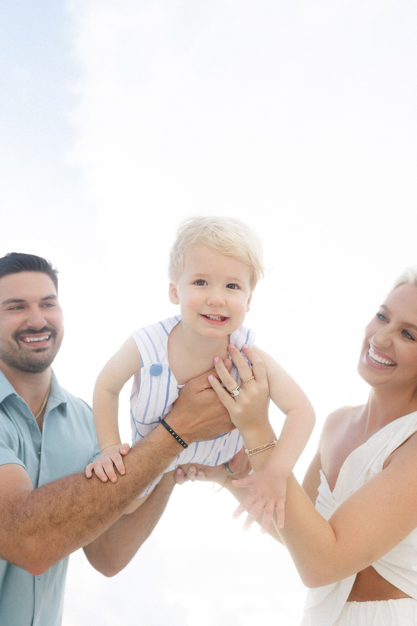 A mother and father playing with their son during their outdoor family photos in Grand Forks
