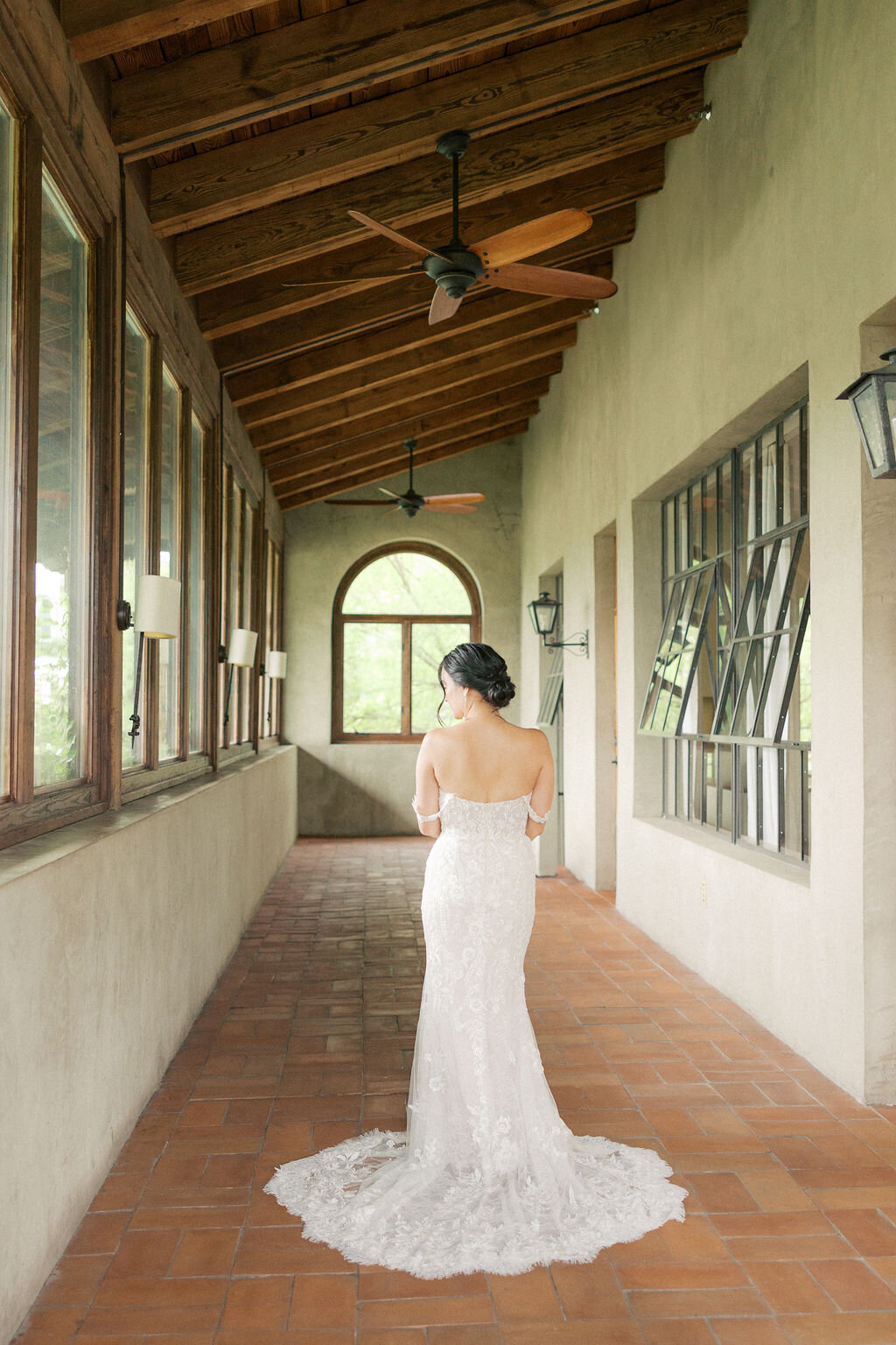 Bride in white lace dress stands under outdoor patio of Summerour Studio