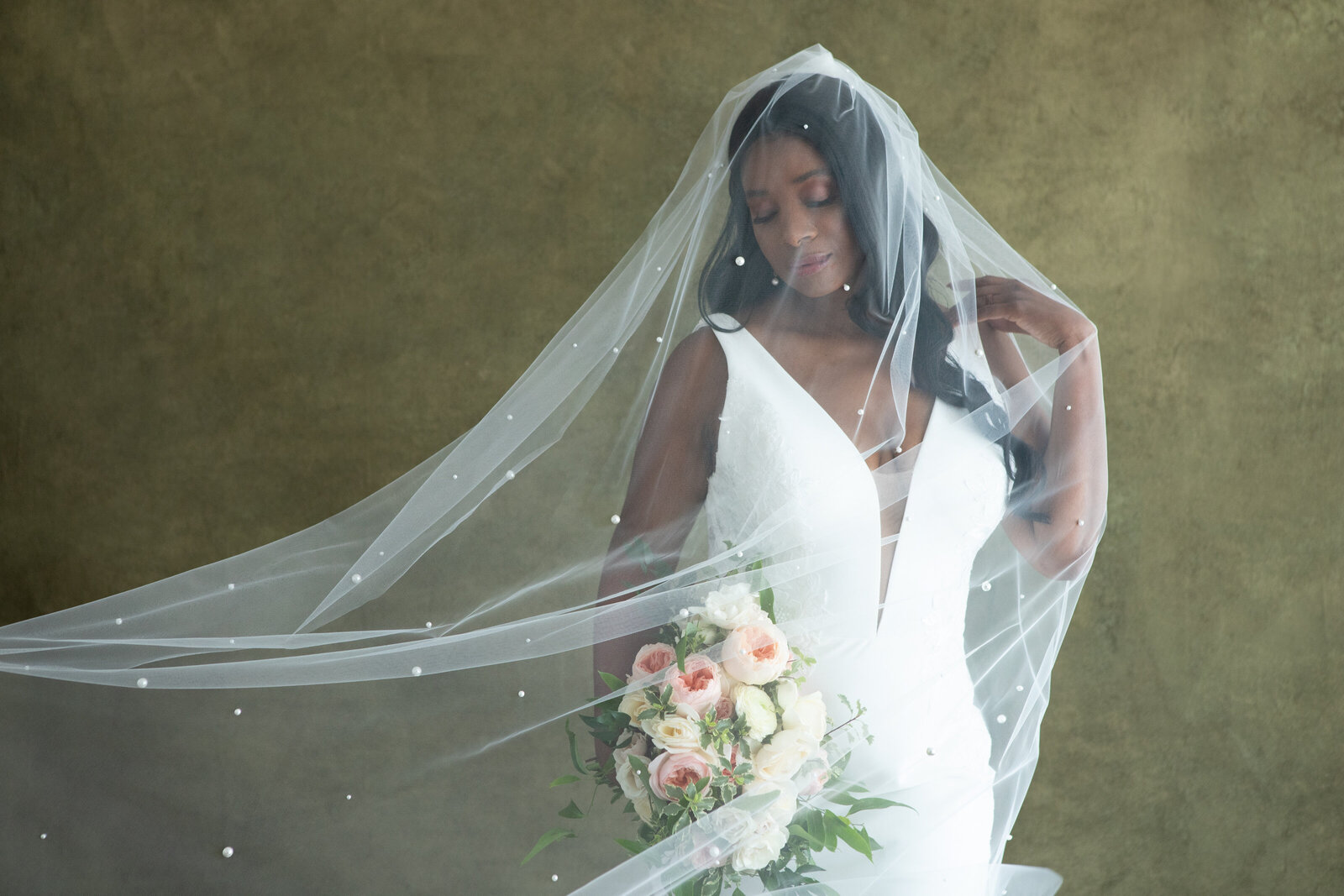 bride wearing a pearl veil and holding a bouquet