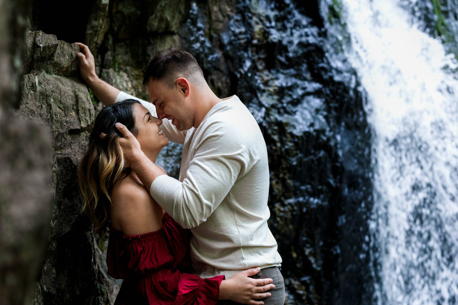 Man embracing his fiance against rock at Kilgore Falls in Maryland