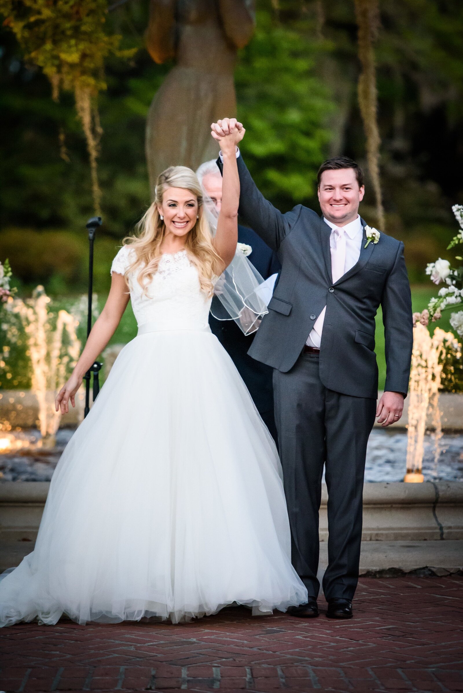 Bride and groom celebrate with hands in the air at Pavilion of the Two Sisters wedding
