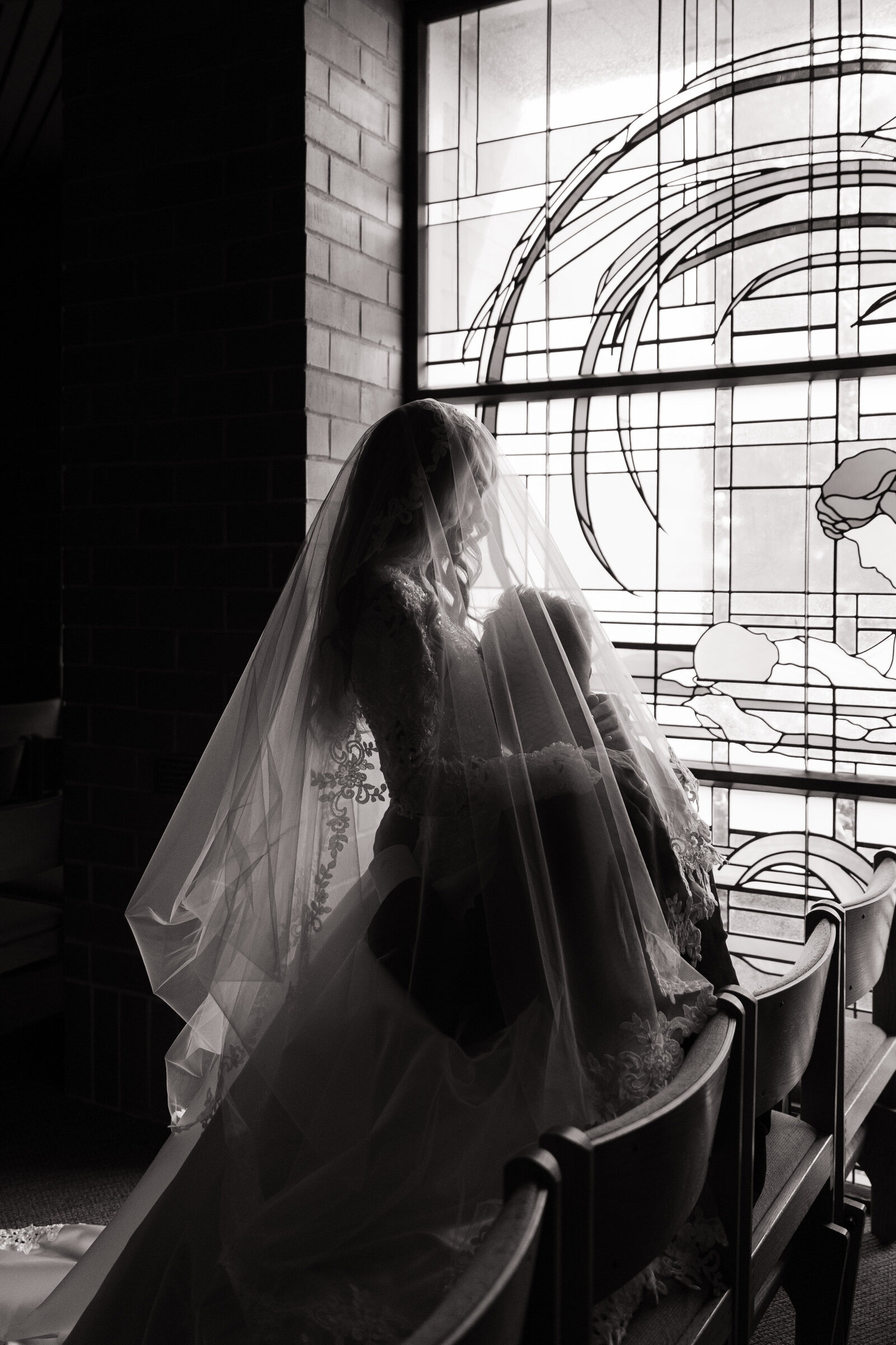 Close up portrait of couple embracing in front of stained glass windows for church wedding in Boise