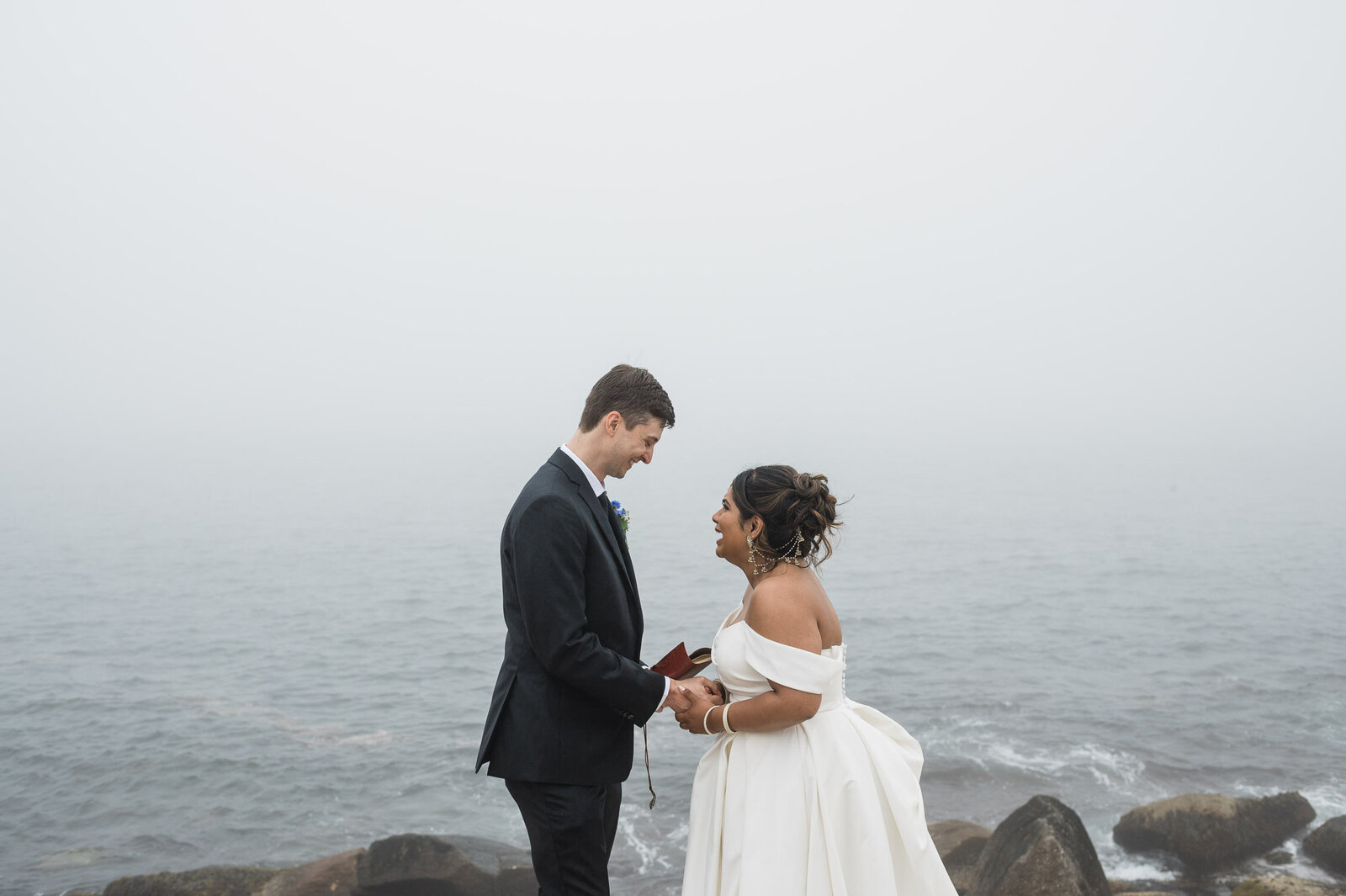 Intimate moment between bride and groom with ocean backdrop.