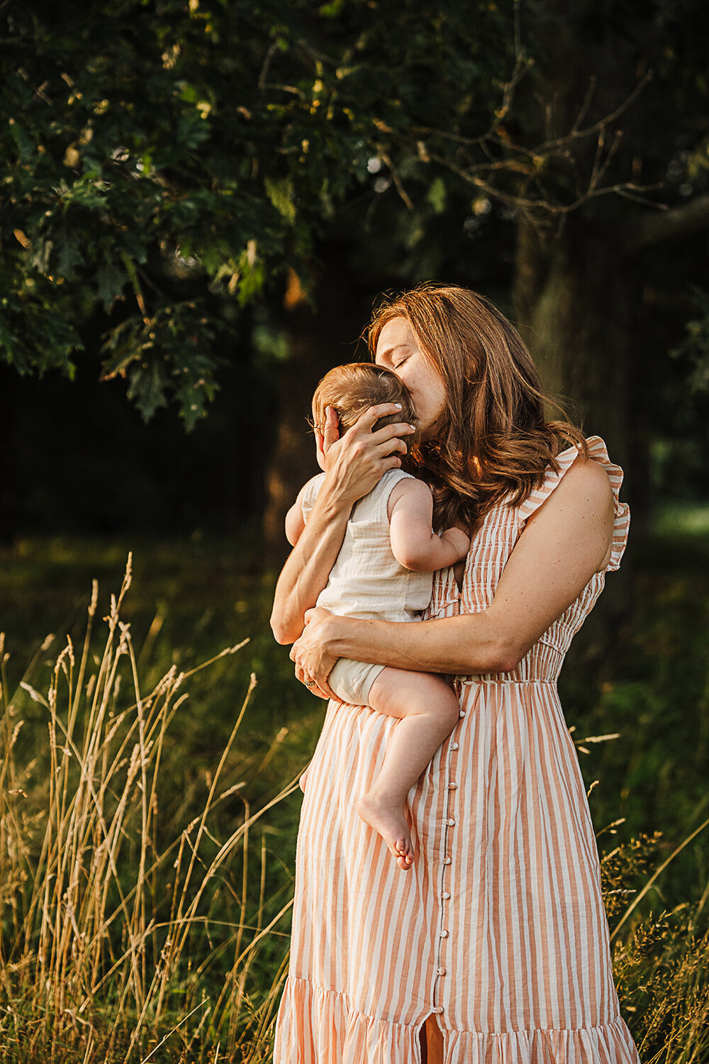 mom holds baby to chest in golden light