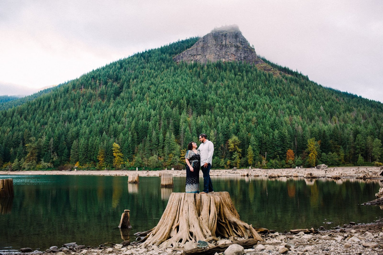 Couple on top of treestump kissing in PNW mountainside session