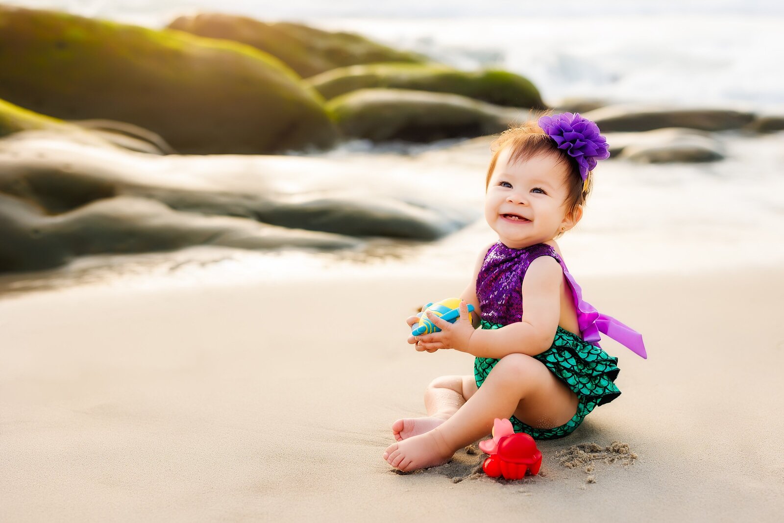 Baby girl dressed as mermaid posing playing on the beach in La Jolla