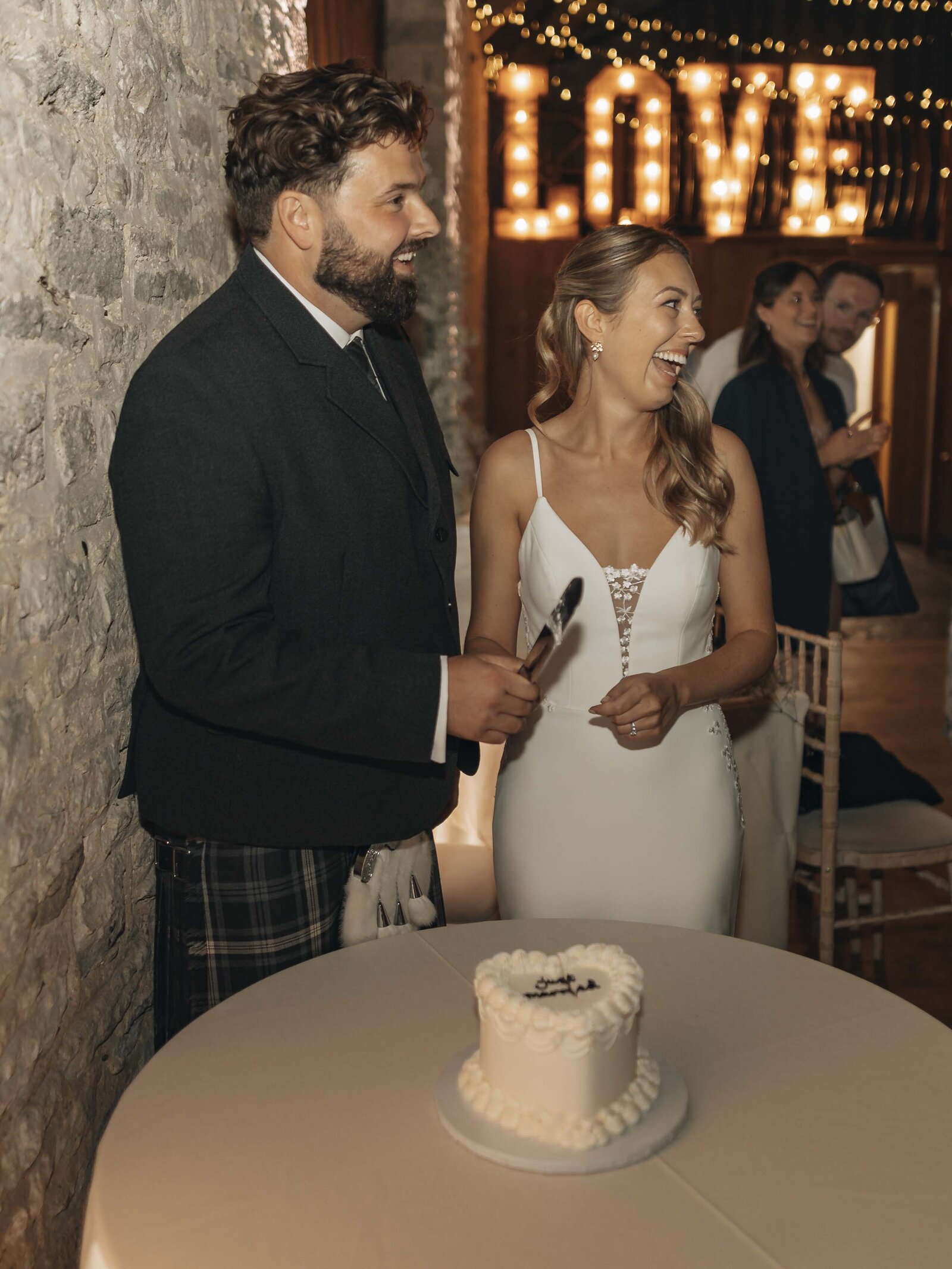 bride and groom laughing, cake cutting photo
