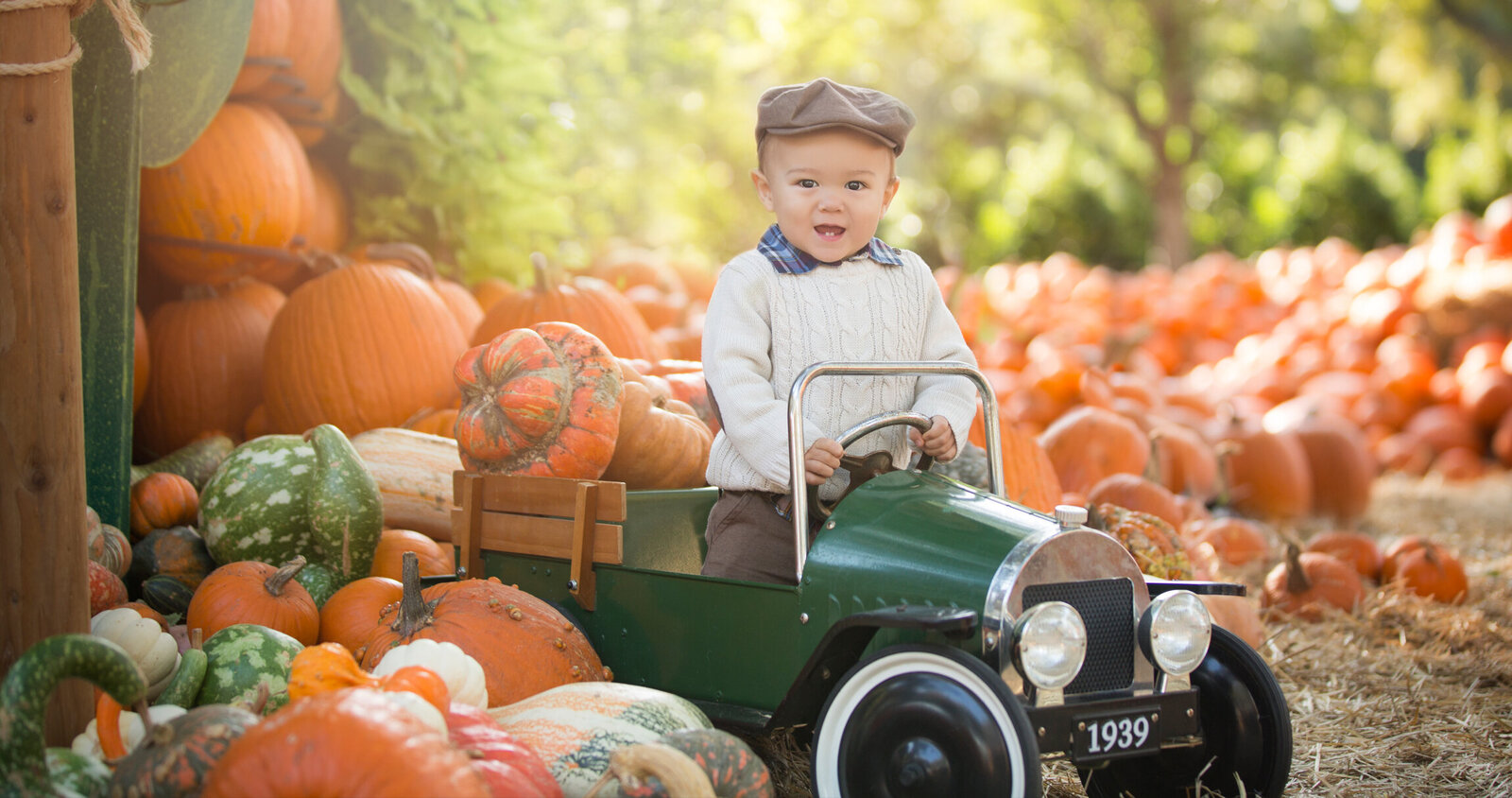 Little boy in vintage car at pumpkin patch.