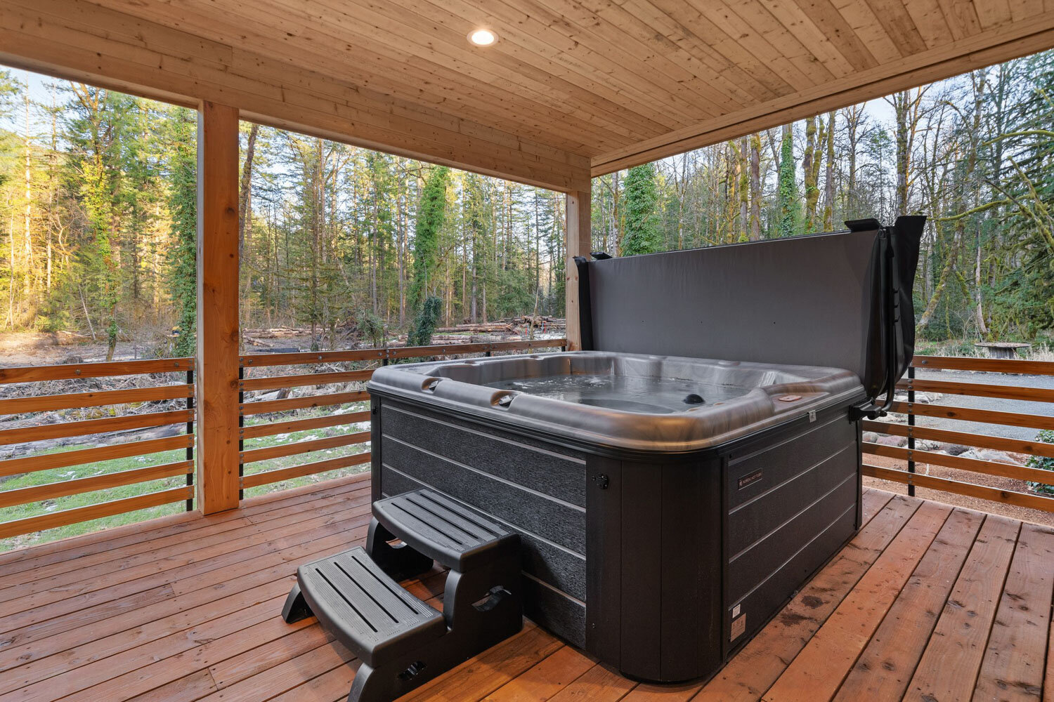 Wooden deck featuring a hot tub with forest views