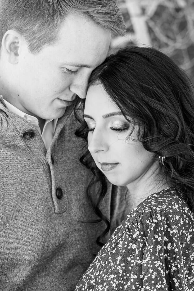 B&W fine art utah engagement photography of a closeup of a man resting his forehead on his fiancee's temple as she looks down with a soft smile on her face