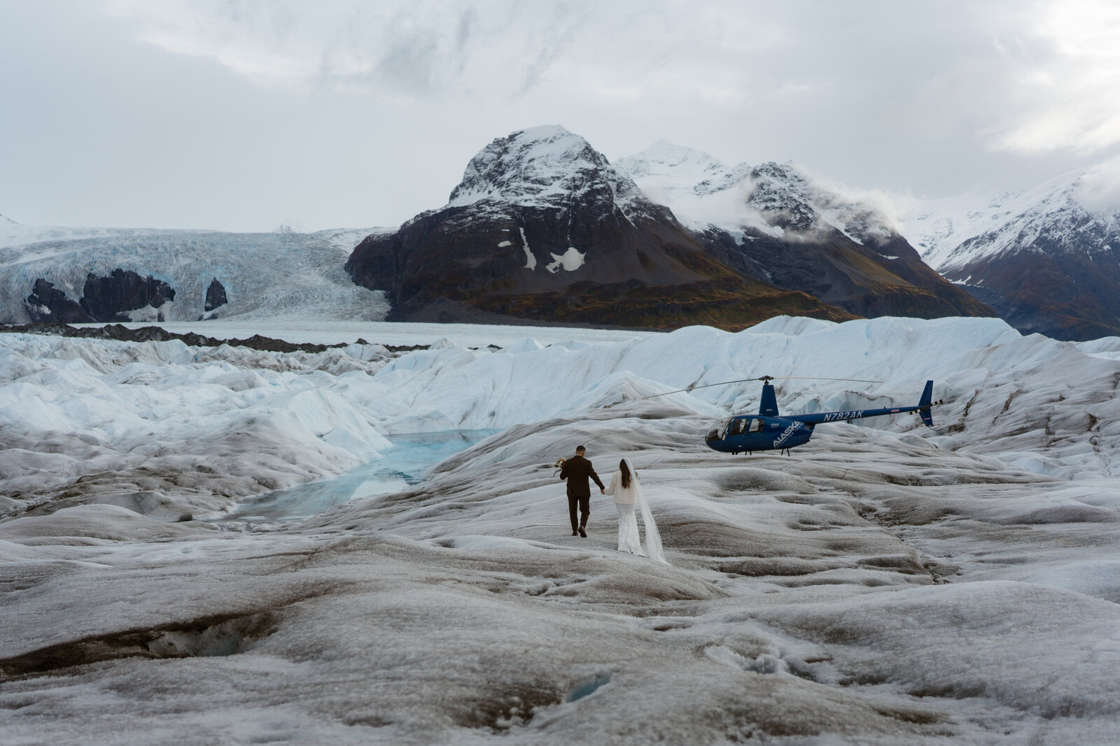 bride and groom and helicopter on glacier