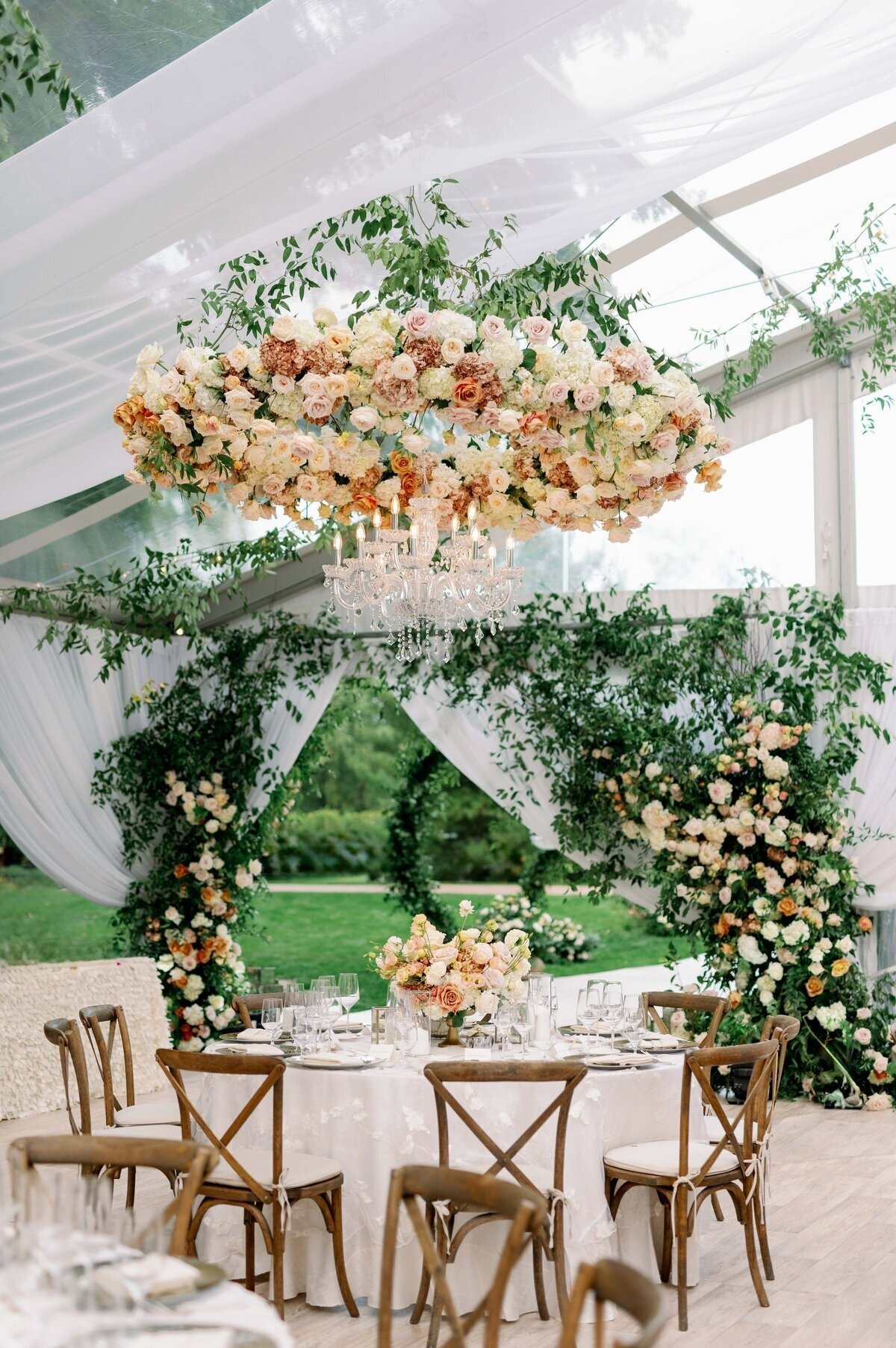 lush peach floral and greenery adorn set tables and chairs under canopy outside for minneapolis wedding reception