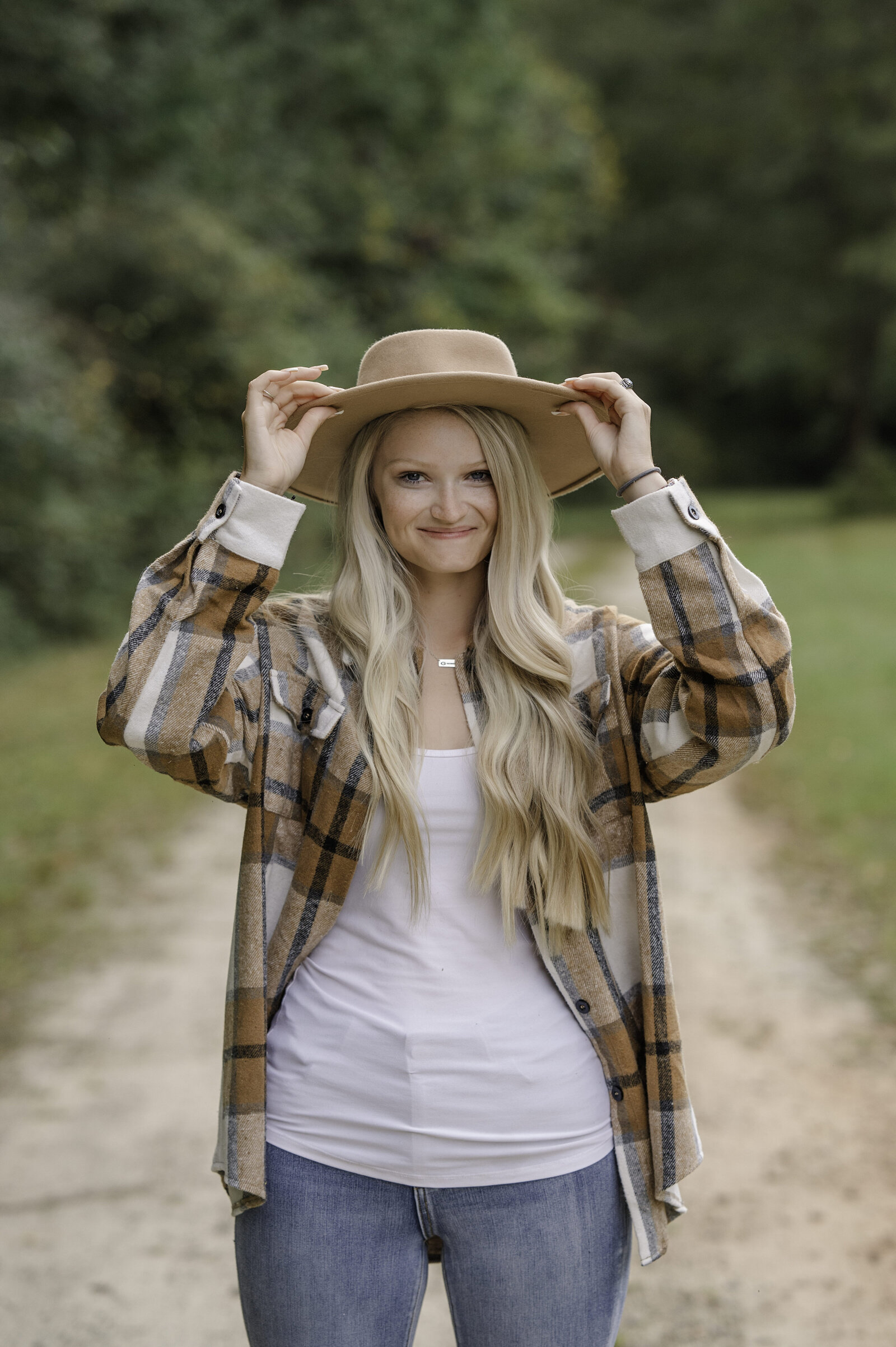 Blonde senior wears a brown hat and smiles