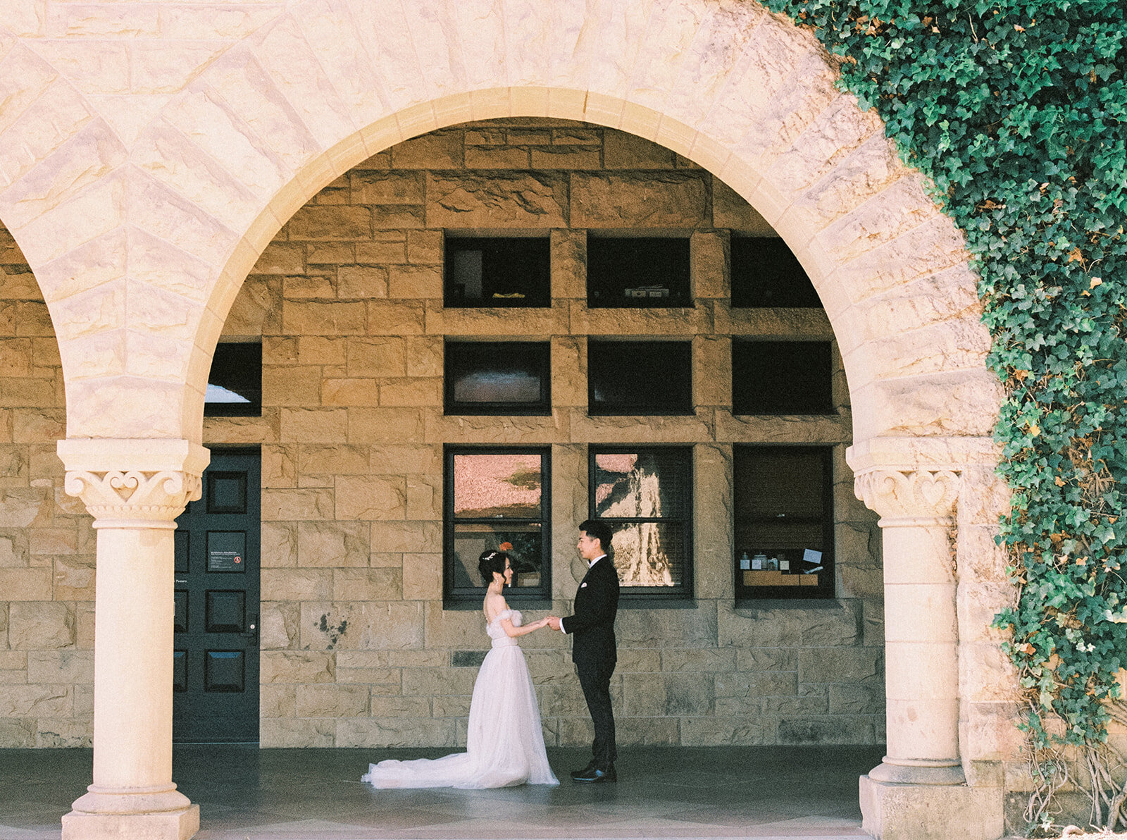 The bride and groom share a romantic moment under an archway at Stanford University, California.