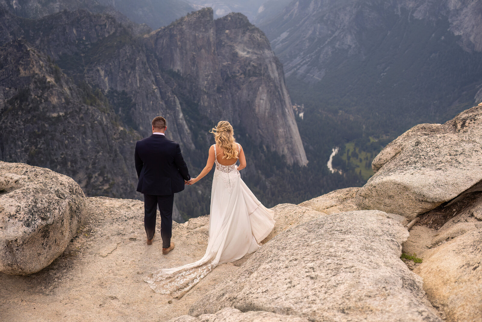 couple looking over a cliff at yosemite on their wedding day