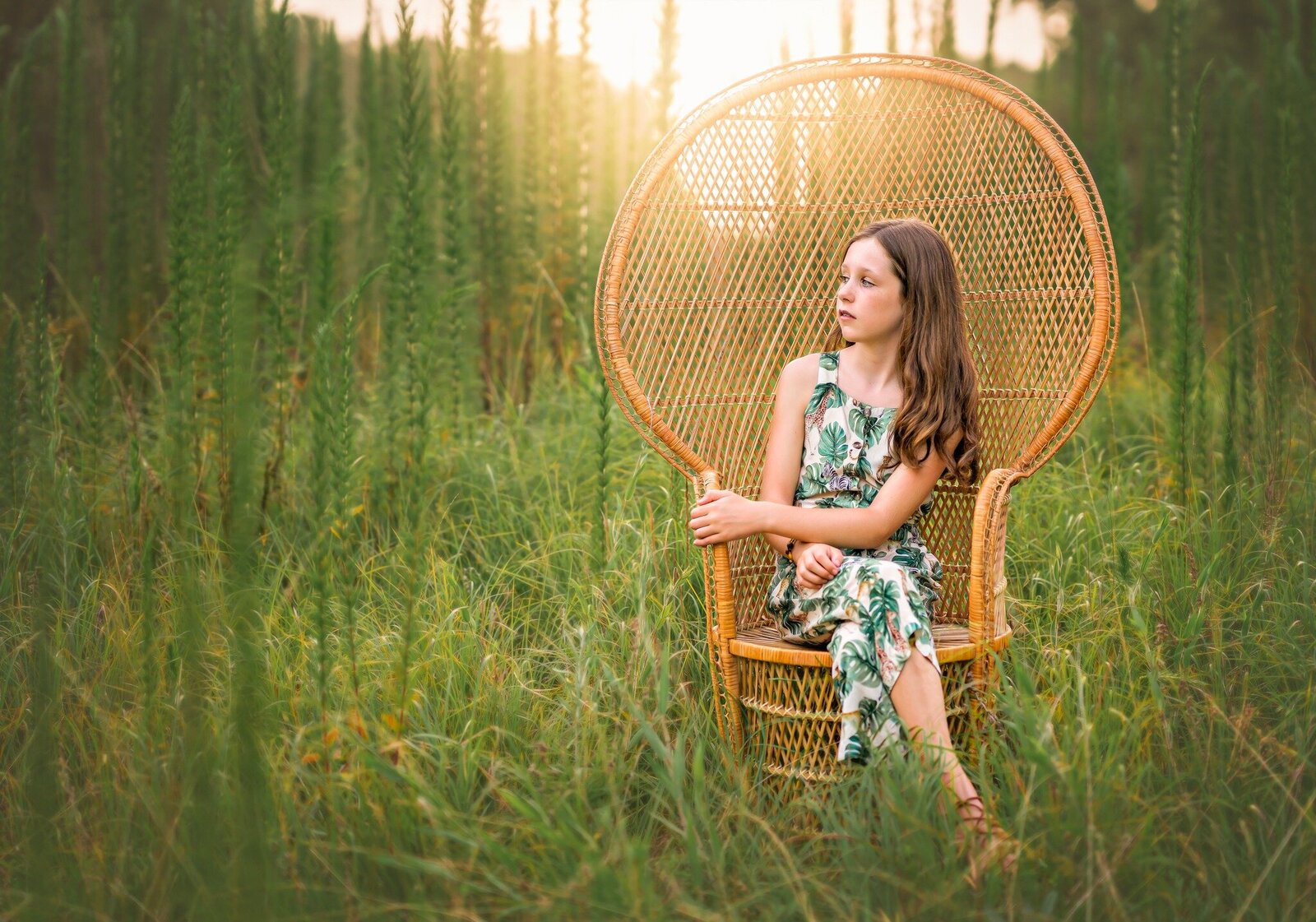 A young girl is sitting in a peacock chair in a field in Newnan, GA.