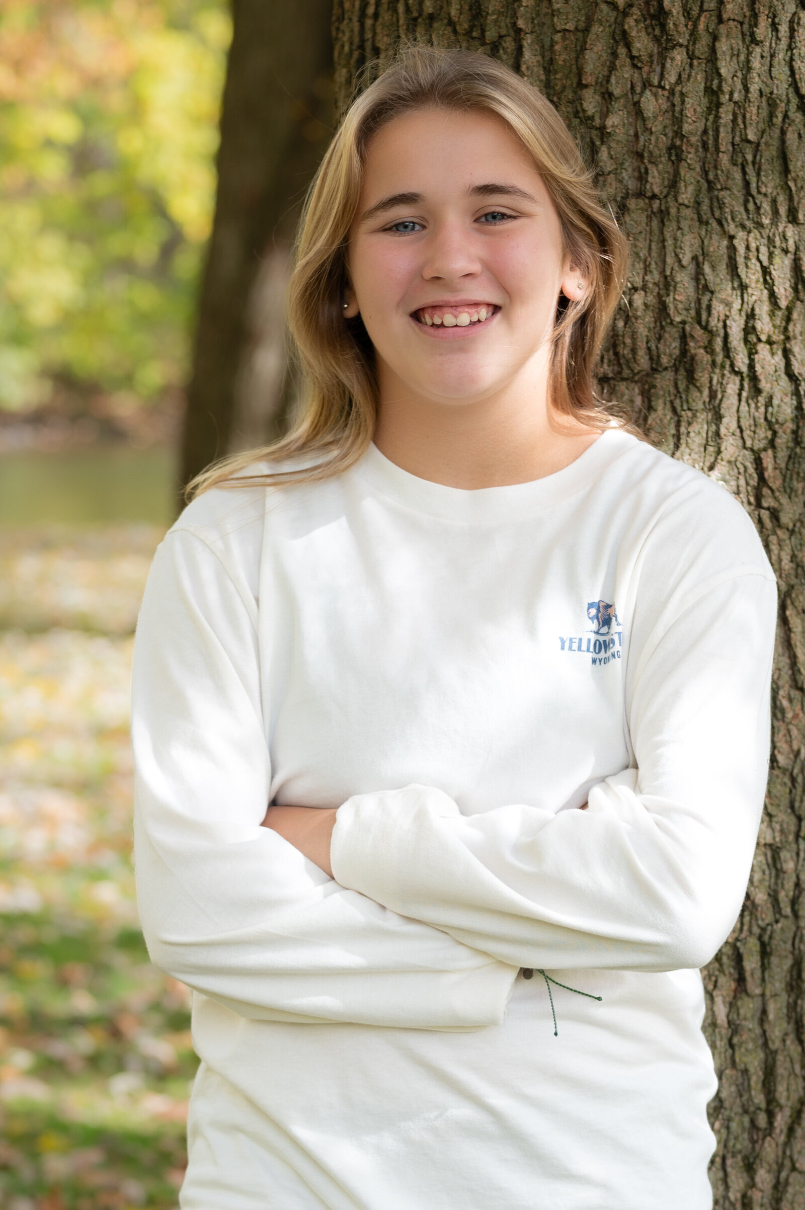 young girl leans against tree for school picture