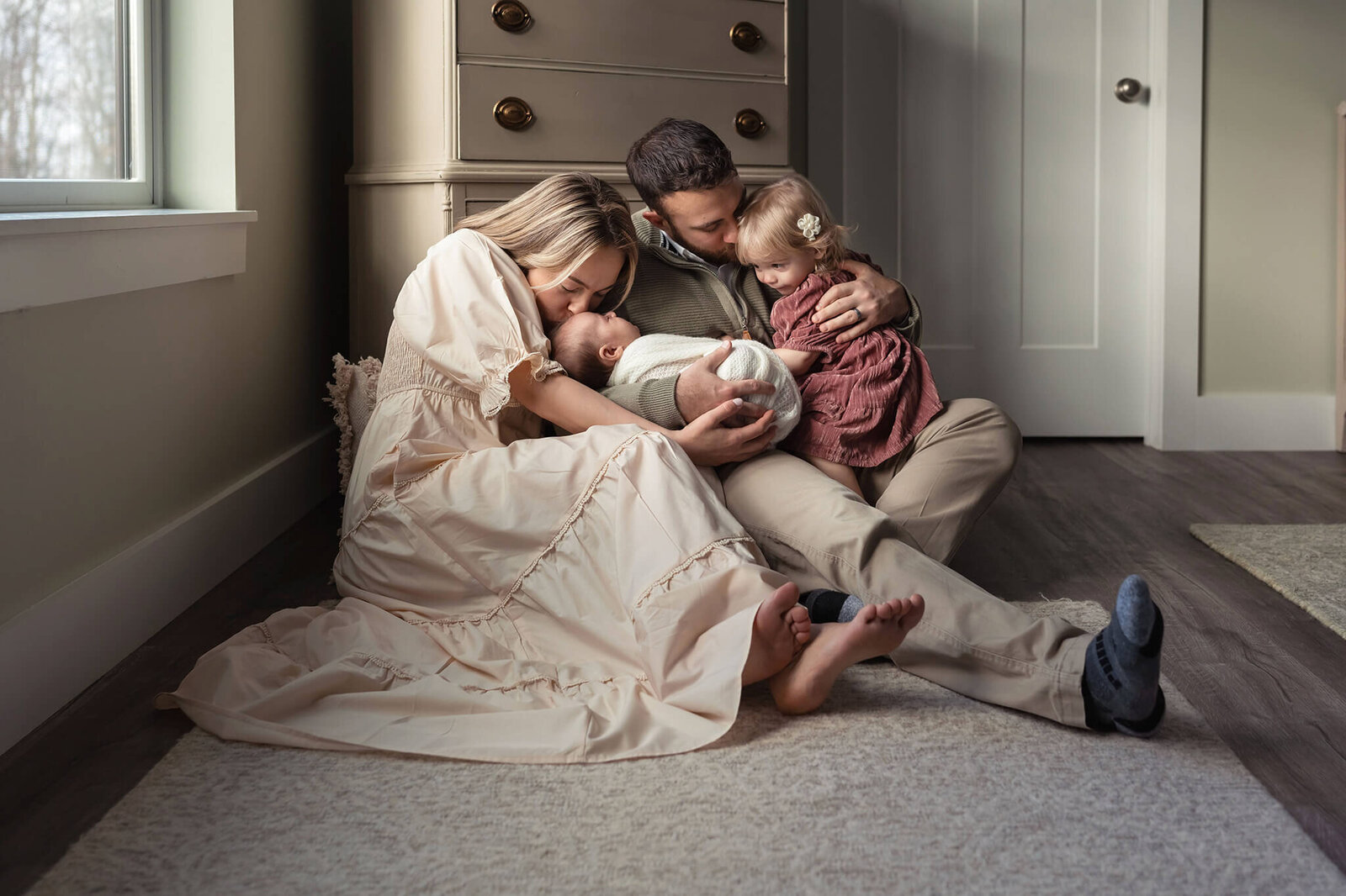 Mom kisses new baby while dad kisses big sister
