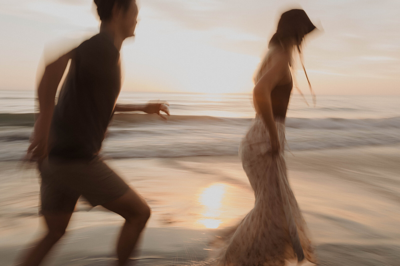 couple running through ocean at sunset