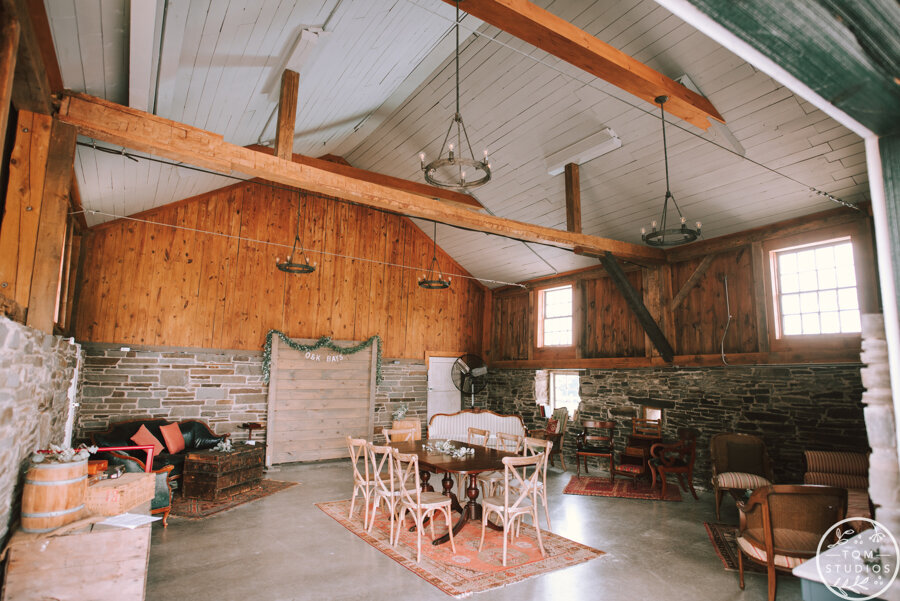 stone and wood interior space of white barn at Windridge Estate with vintage furniture