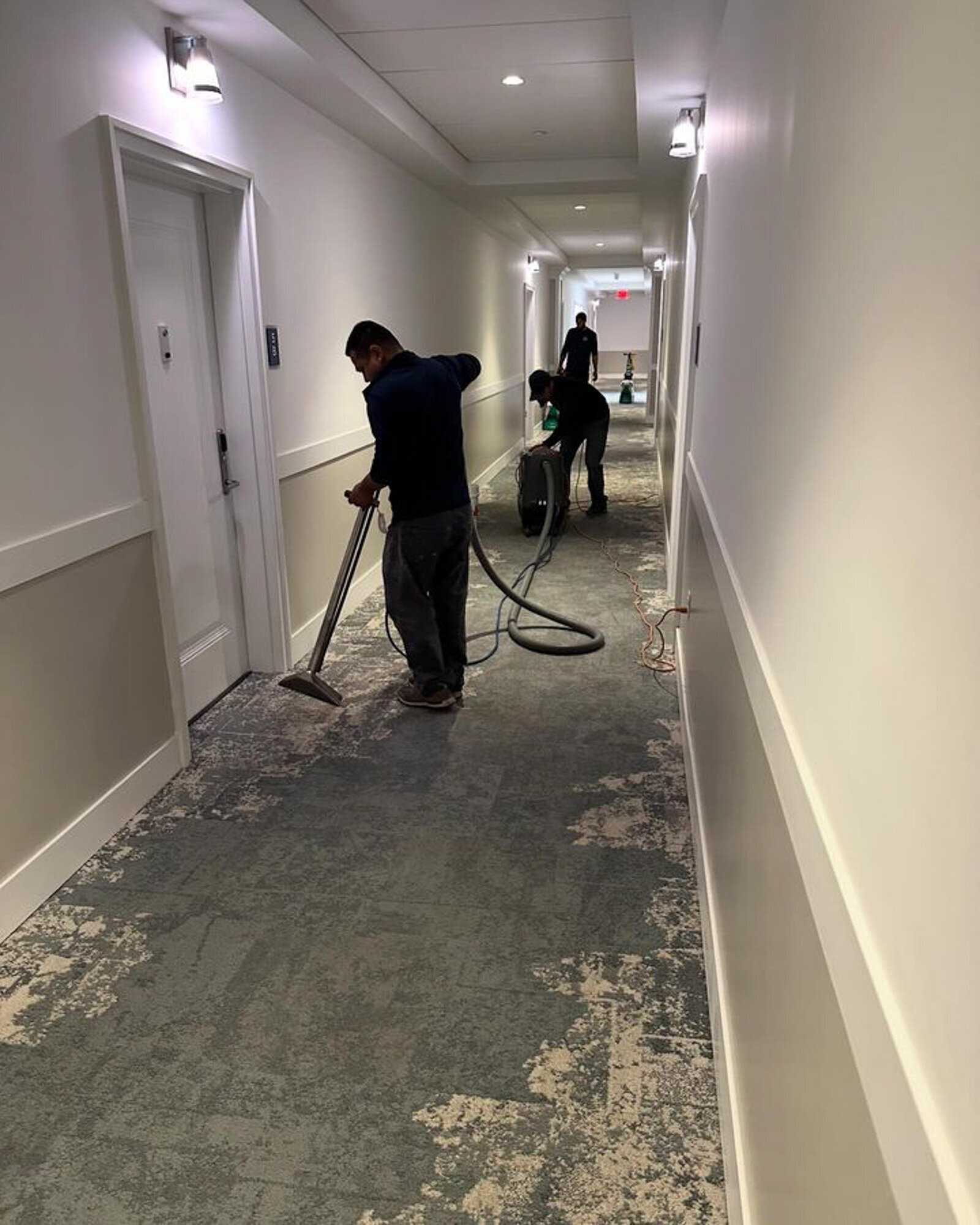 Team vacuuming and cleaning a hotel hallway